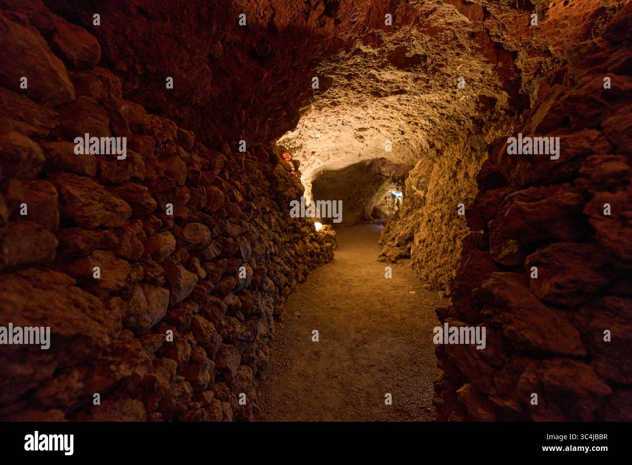 Intérieur d'une grotte volcanique formée par un ancien tube de lave avec des murs en pierre brute et un éclairage tamisé Banque D'Images