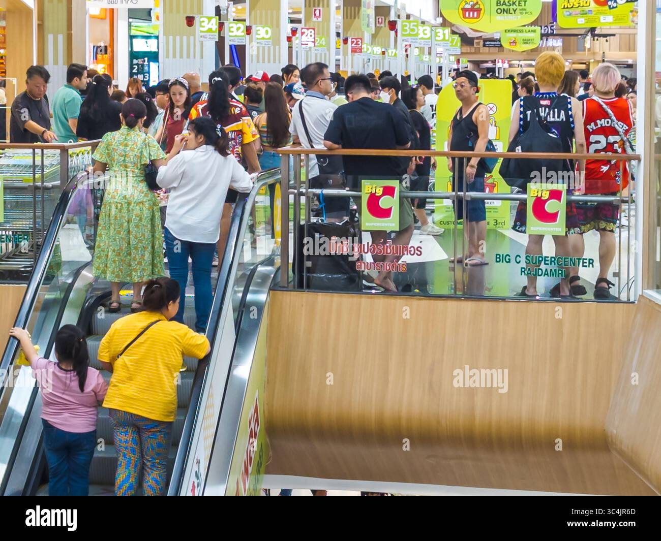 Thaïlande-03 juillet 2024 : rayon vêtements et escaliers mécaniques à l'intérieur d'une grande branche occupée de la chaîne de magasins de détail populaire, comme beaucoup de clients magasinent pour i. Banque D'Images
