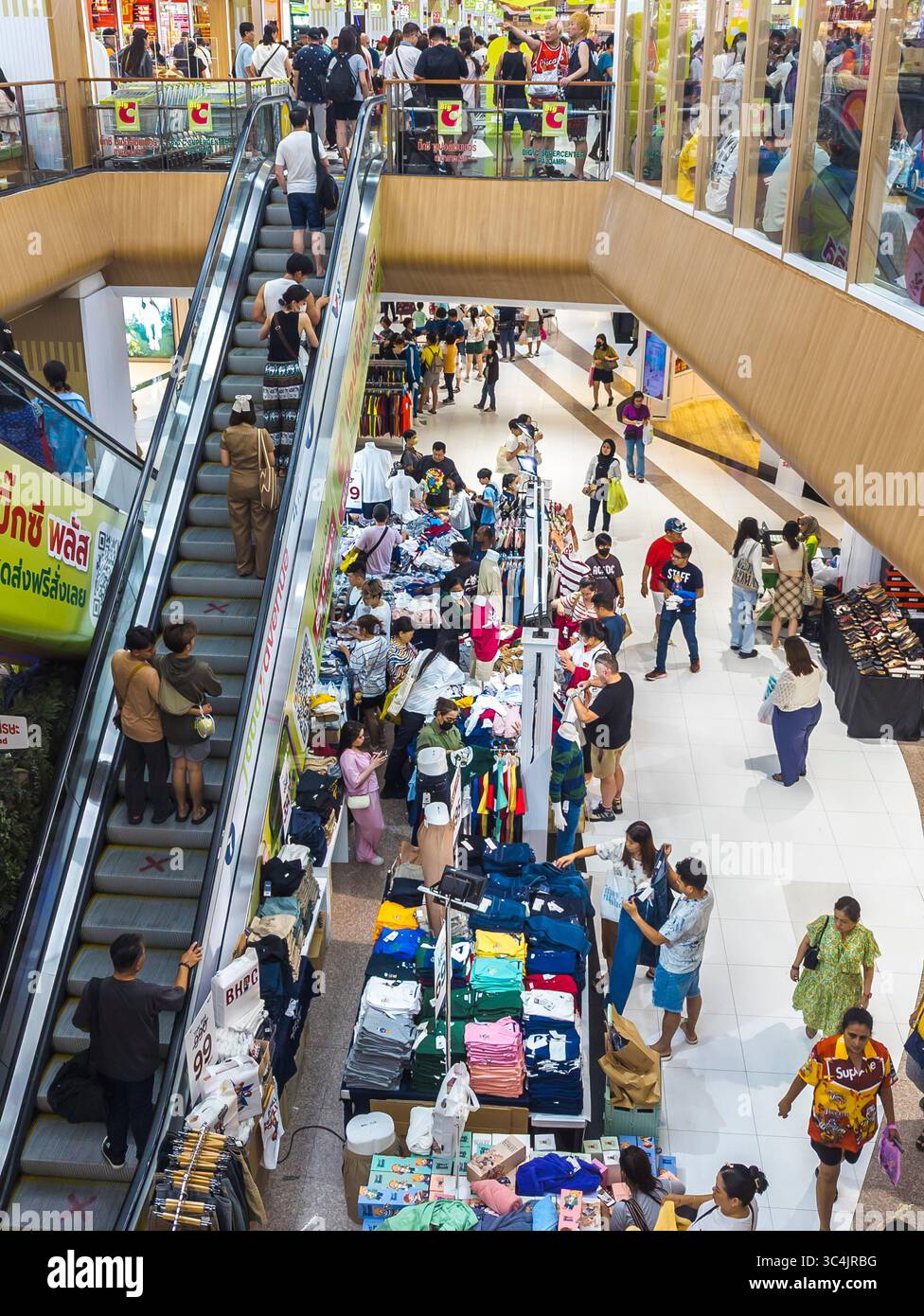 Thaïlande-03 juillet 2024 : rayon vêtements et escaliers mécaniques à l'intérieur d'une grande branche occupée de la chaîne de magasins de détail populaire, comme beaucoup de clients magasinent pour i. Banque D'Images