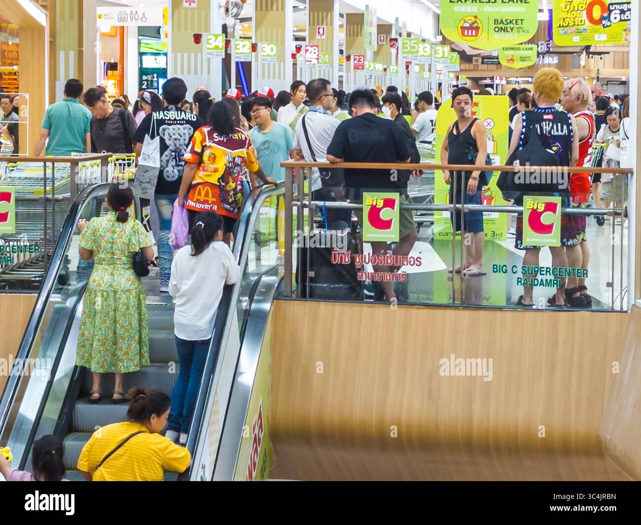 Thaïlande-03 juillet 2024 : rayon vêtements et escaliers mécaniques à l'intérieur d'une grande branche occupée de la chaîne de magasins de détail populaire, comme beaucoup de clients magasinent pour i. Banque D'Images