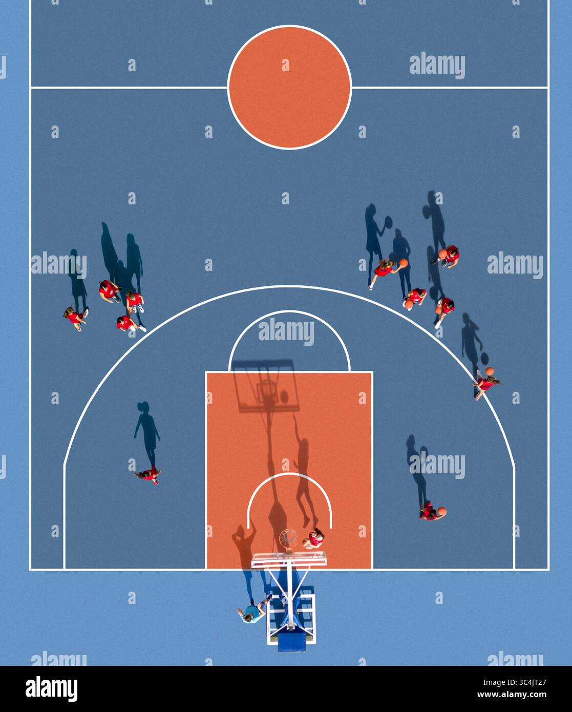 Vue aérienne d'un terrain de basket-ball orange éclatant contrastant avec le bleu frais, tandis que les joueurs projettent de longues ombres sur le sol, Valence, Communauté valencienne, Espagne. Banque D'Images