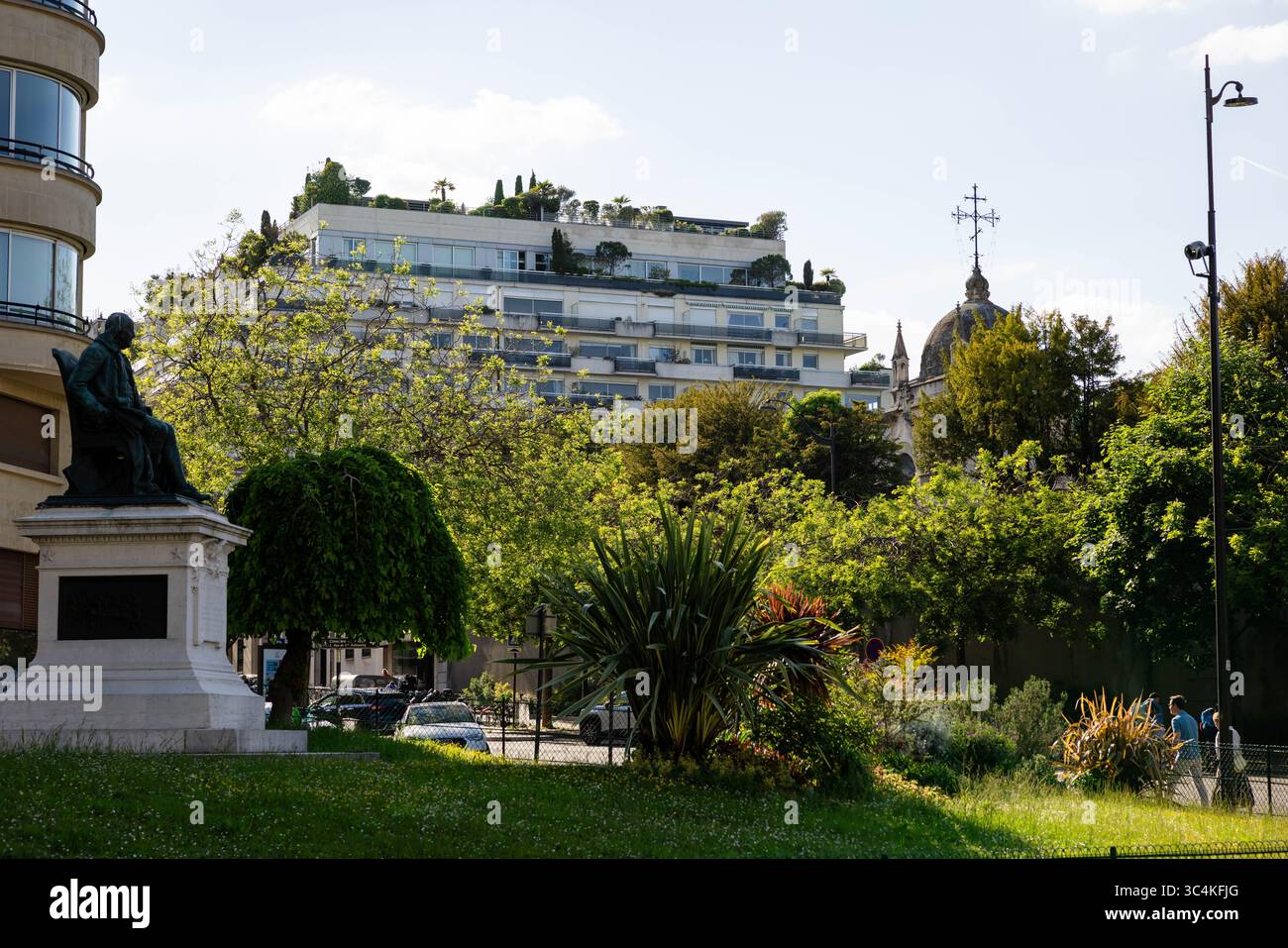 Un paysage urbain parisien avec une statue, une végétation luxuriante et un immeuble moderne avec un jardin sur le toit. L'ambiance est sereine et paisible, idéal Banque D'Images