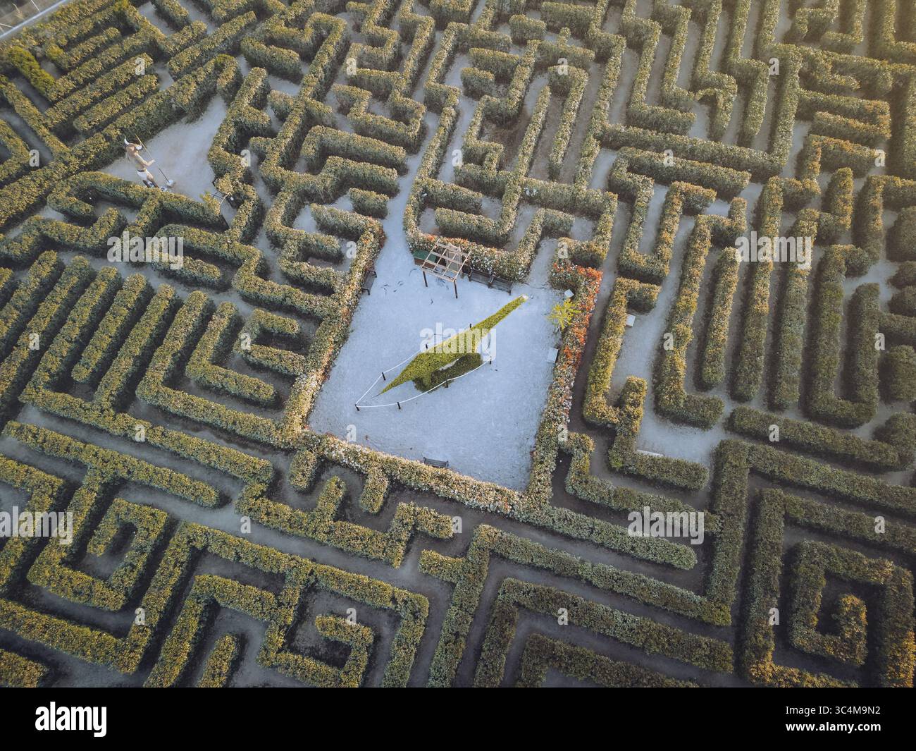 Vue aérienne du labyrinthe labyrinthique de maïs, un puzzle de sentiers verts et statue cachée de dinosaures, baigné dans la douce lueur du crépuscule, Peñíscola, Comunidad Valenciana, Espagne. Banque D'Images