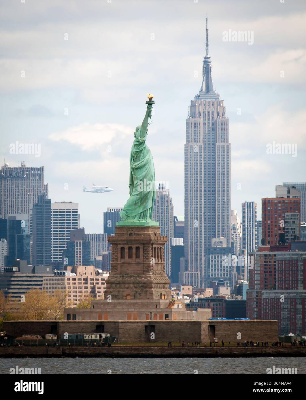 La navette spatiale Enterprise, montée sur un avion NASA 747 Shuttle Carrier (SCA), est vue au loin derrière la Statue de la liberté, vendredi, AP Banque D'Images