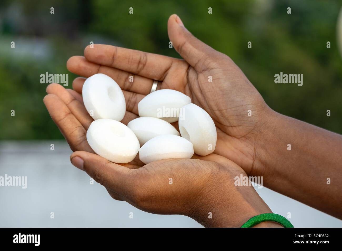 Main féminine tenant de grosses billes blanches de naphtalène. Polyvalent pour les sujets sur les boules de mouton, le goudron blanc et la lutte contre les parasites à la maison. Idéal pour la santé, la sécurité, et ho Banque D'Images
