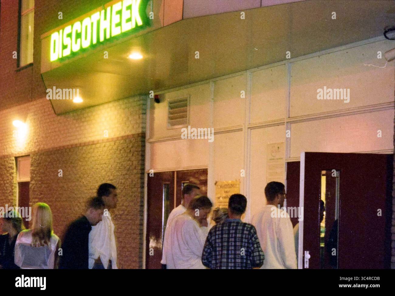 Discothèque People for the Challenge à Hoofddorp, Hoofddorp, Nederland, 26-09-1997 Whizgle News, Dutch Desk, pays-Bas, 1950-2000 Un groupe de personnes habillées dans des tenues élégantes est rassemblé à l'extérieur d'une discothèque vibrante avec une signalisation lumineuse, attendant impatiemment d'entrer et de profiter d'une nuit de musique et de danse. Banque D'Images