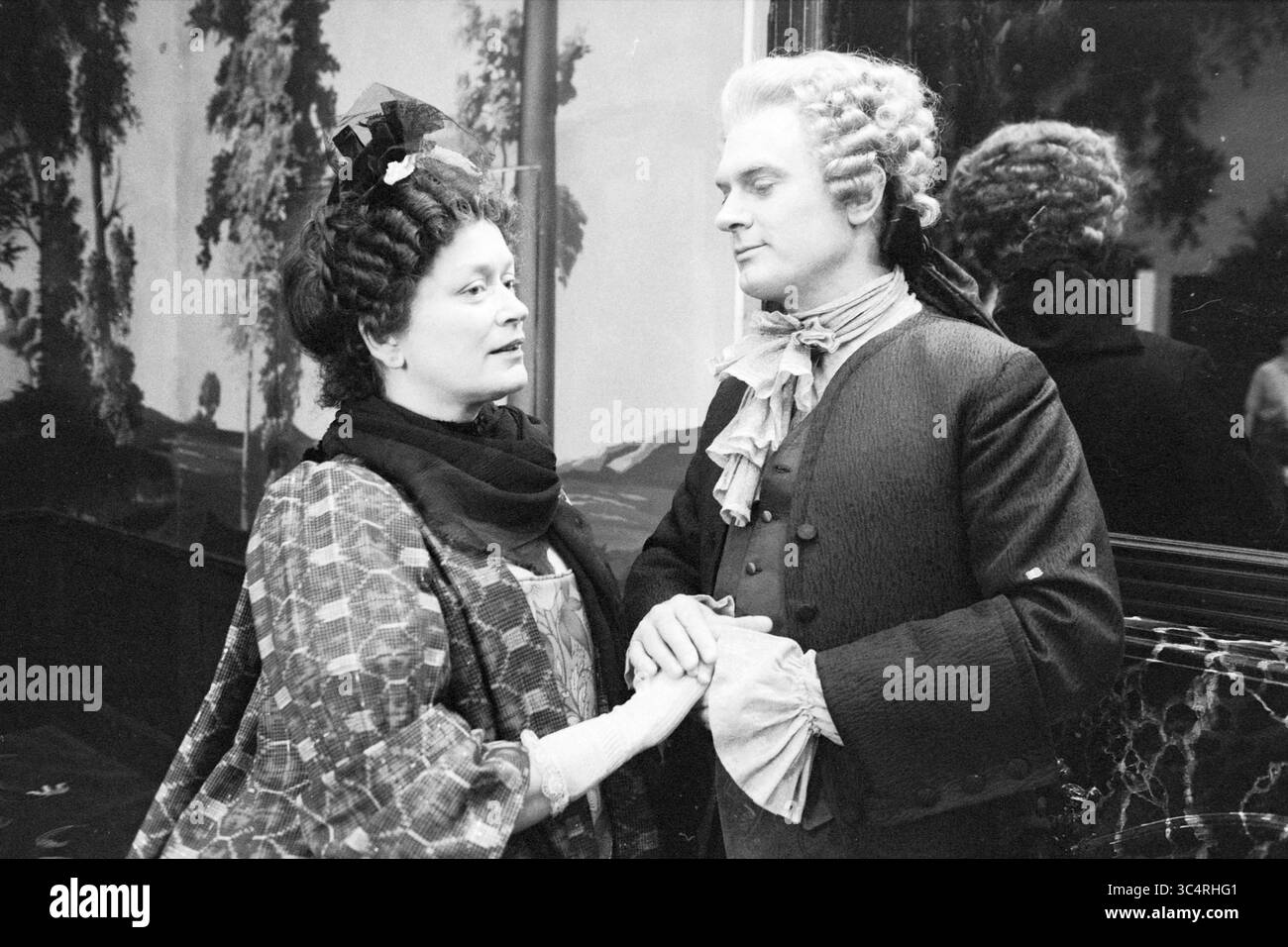 Répétition théâtrale 'scandale en Hollande' avec Henriette Tol, Carol van Herwijnen, Peter Blok, Ben Huisman, Amsterdam, pays-Bas, 12-03-1983 Whizgle News, Dutch Desk, pays-Bas, 1950-2000 Une femme et un homme élégamment habillés s'engagent dans une conversation réfléchie, leurs coiffures élaborées et leurs vêtements d'époque reflétant la mode d'une époque révolue. La toile de fond présente un paysage doux, ajoutant une ambiance romantique à la scène. Banque D'Images