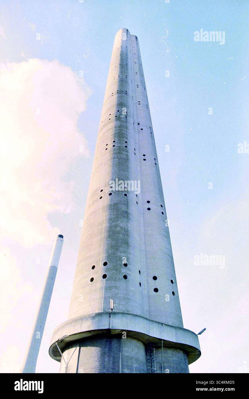 UNA Chimney 3-2-1998, Velsen, 27-09-1998 Whizgle News, Dutch Desk, pays-Bas, 1950-2000 Une grande structure conique en béton brut, comportant une série de trous régulièrement espacés le long de sa surface, s'élève bien en évidence contre un ciel clair. À proximité, une cheminée plus petite est visible en arrière-plan, ajoutant à l'atmosphère industrielle. Banque D'Images