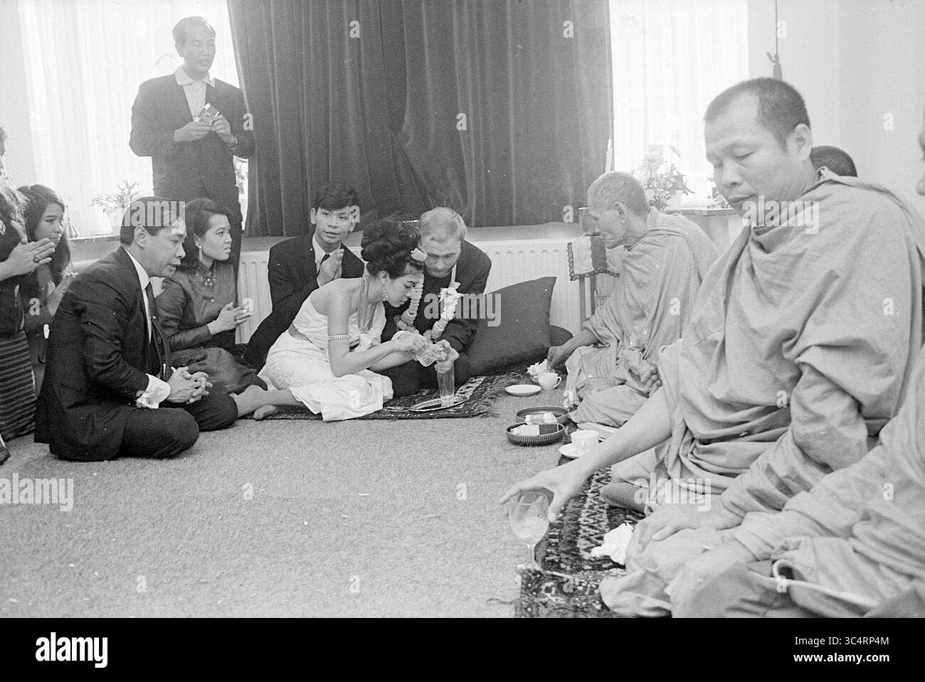 Mariage bouddhiste avec grand prêtre de Thaïlande, Heemstede, pays-Bas, 10-11-1968 Whizgle News, Dutch Desk, pays-Bas, 1950-2000 Une cérémonie réunissant une mariée et un marié engagés dans un rituel traditionnel, entourés de famille et d'amis. Les moines observent la procédure, ajoutant un élément spirituel à la célébration, tandis que l'atmosphère est une atmosphère de vénération et de joie. Banque D'Images