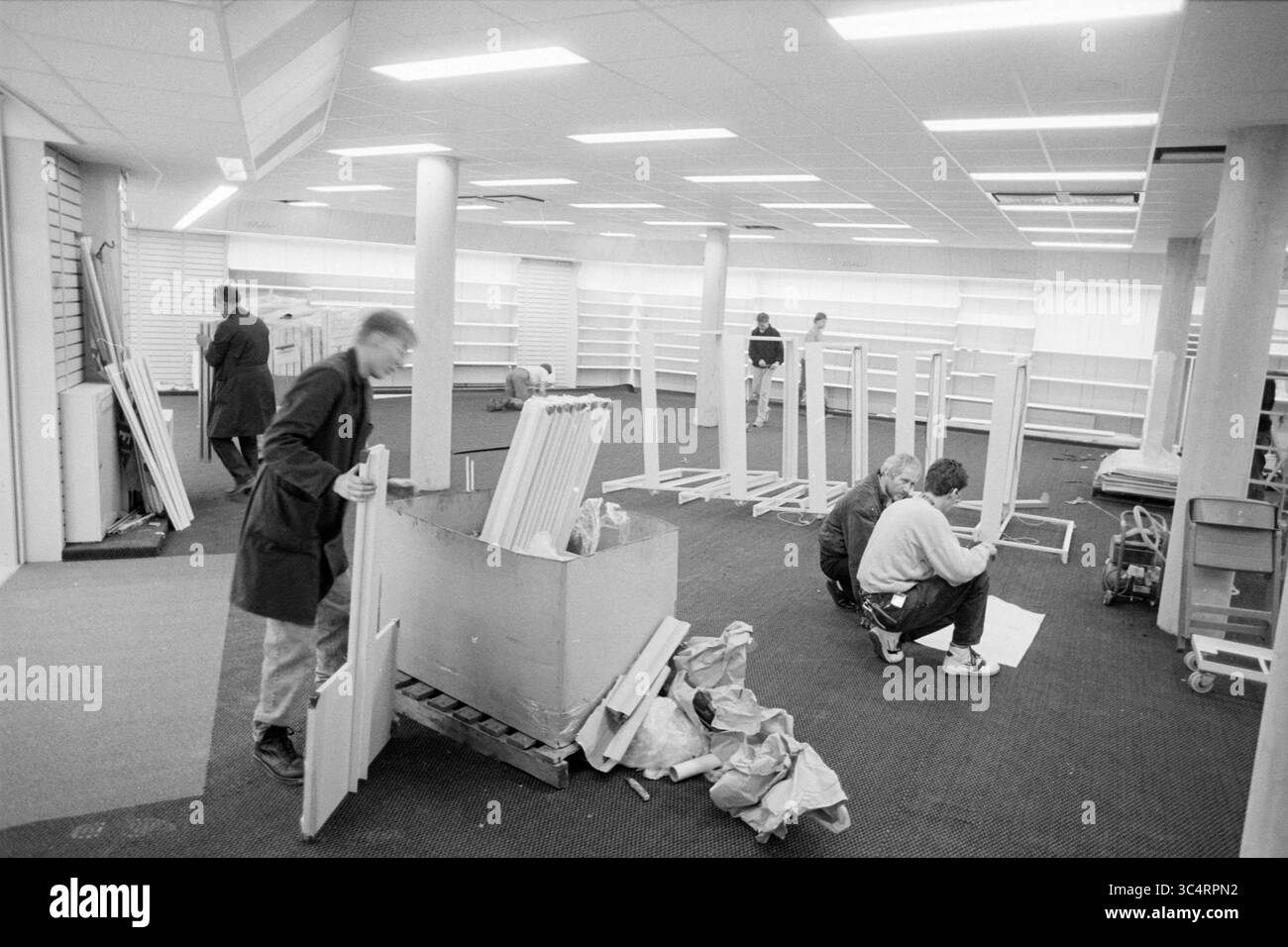 Conception d'un nouveau centre commercial à Hoofddorp, Hoofddorp, Polderplein, pays-Bas, 07-10-1992 Whizgle News, Dutch Desk, pays-Bas, 1950-2000 Un groupe de personnes est engagé dans la mise en place d'un espace de vente au détail, l'agencement des étagères et l'assemblage des meubles alors que le chaos organisé les entoure. Certains se concentrent sur l'assemblage des articles, tandis que d'autres manipulent des matériaux, contribuant à la transformation du magasin vide en un environnement fonctionnel. Banque D'Images