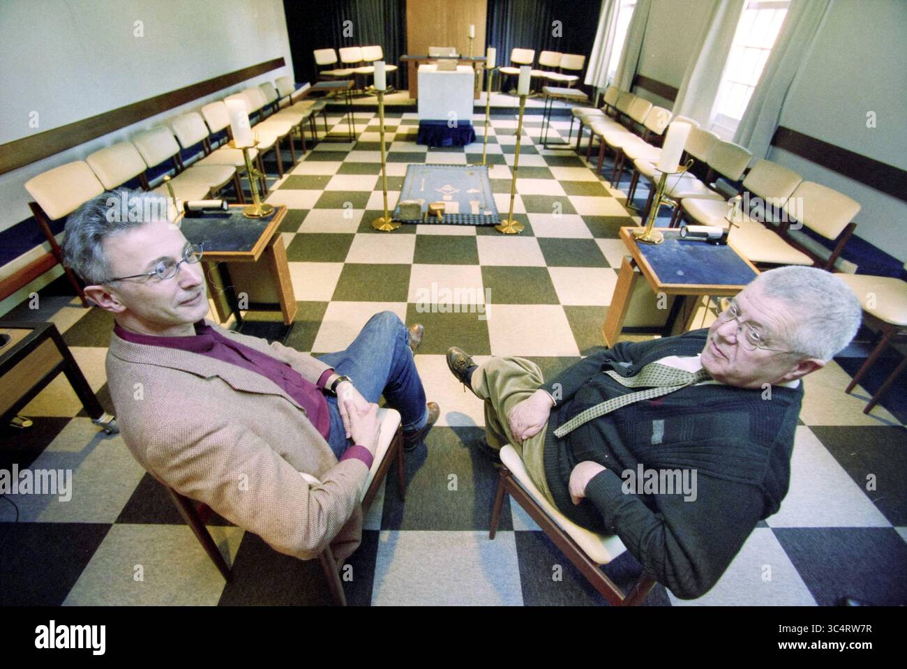 Francs-maçons de Hoeksteen, Velsen, Velsen-Zuid, 14-02-2001 Whizgle News, Dutch Desk, pays-Bas, 1950-2000 deux personnes sont assises dans une salle avec un plancher en damier, entourée de chaises disposées en cercle. Le cadre semble être un espace formel, éventuellement pour une réunion ou une discussion, avec un podium à l'avant et un écran de projection visible. L'atmosphère suggère de mettre l'accent sur le dialogue ou la présentation. Banque D'Images