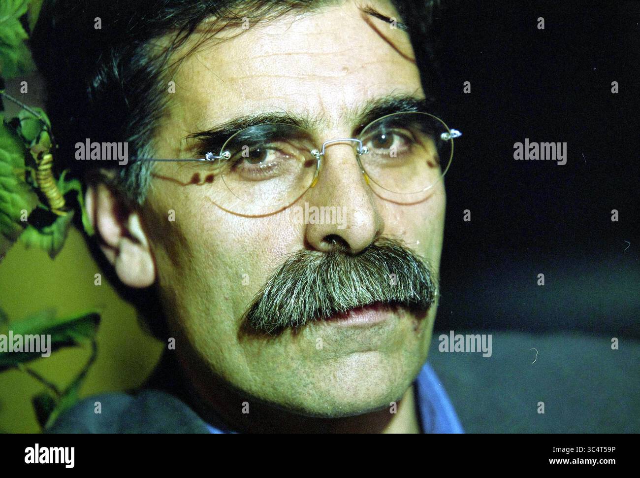 Écrivain Kader Abdolah, Hoofddorp, pays-Bas, 05-02-2001 Whizgle News, Dutch Desk, pays-Bas, 1950-2000 Un homme avec une moustache proéminente et des lunettes regarde avec soin, entouré de verdure. Son expression transmet un sens de contemplation et de profondeur. Banque D'Images