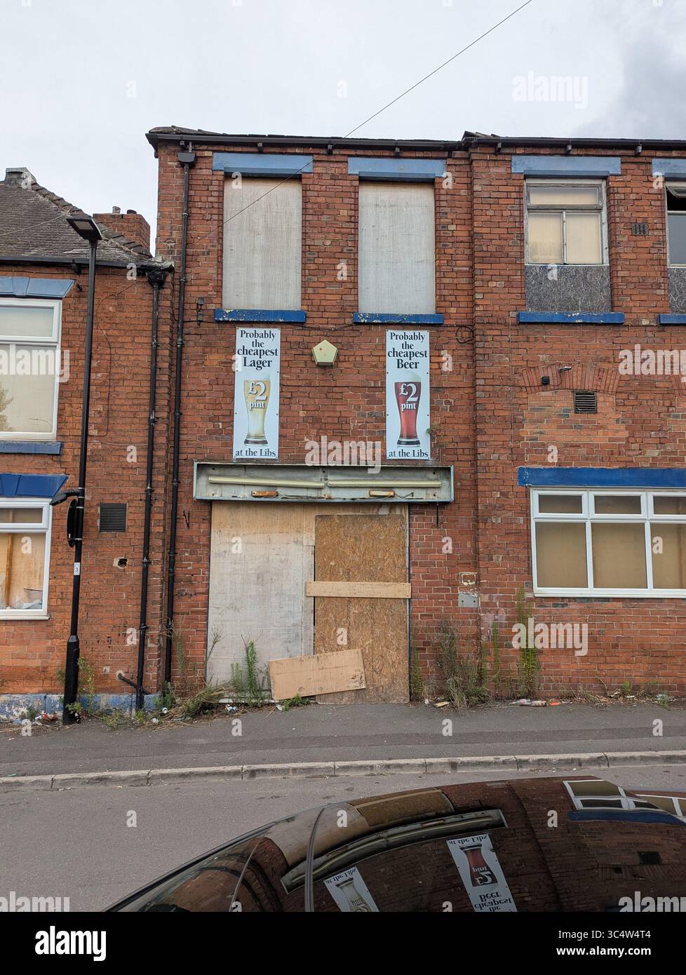 Des enseignes de bière bon marché sur l'ancien bâtiment Attercliffe Liberal Club, Sheffield, South Yorkshire, Royaume-Uni, sont maintenant embarquées et attendent un nouveau développement - Image de stock capturée avec un smartphone