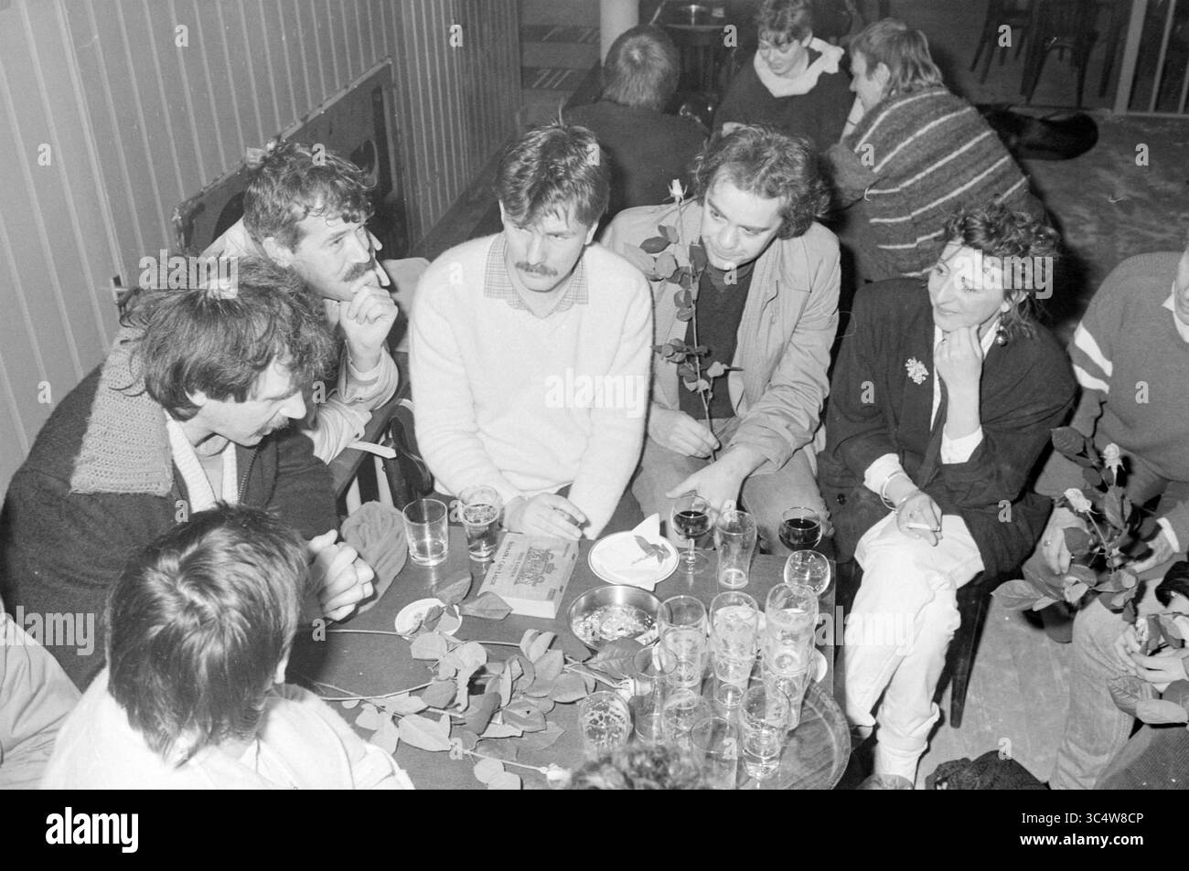 Boissons d'adieu Daniëlle Kraft in the Flapcan, Haarlems Dagblad, etc. and IJmuider courant and Koeri, 02-04-1985 Whizgle News, Dutch Desk, pays-Bas, 1950-2000 Un groupe de personnes se réunit autour d'une table, engagé dans une conversation profonde tout en dégustant un verre. Plusieurs verres à bière et des feuilles dispersées peuvent être vus sur la table, ajoutant à l'atmosphère intime. Les individus présentent une variété d'expressions, suggérant une discussion animée entre amis ou connaissances. Banque D'Images