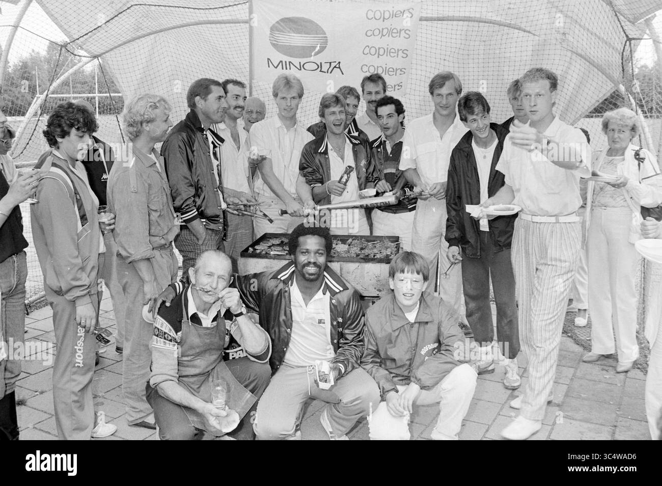 Équipe de baseball Pioniers championnat party, Baseball, 11-08-1985 Whizgle News, Dutch Desk, pays-Bas, 1950-2000 Un groupe animé d'individus se réunit autour d'un barbecue, appréciant la nourriture et la camaraderie. Ils sont habillés de vêtements sportifs décontractés, avec des sourires et des rires partagés entre amis. Une bannière en arrière-plan met en valeur une marque, ajoutant à l’ambiance festive du rassemblement. Banque D'Images