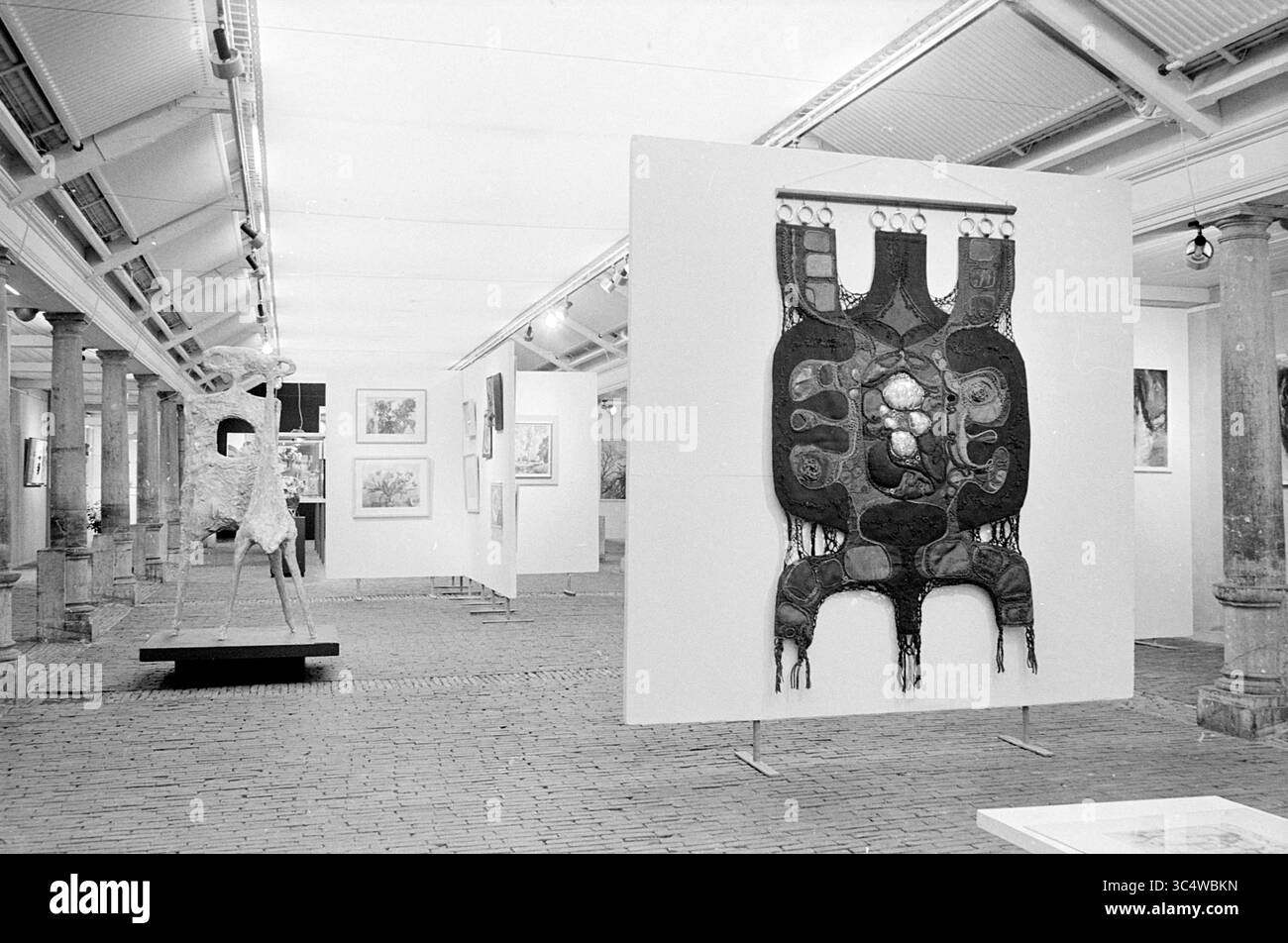 Exposition Vishal, expositions, 18-01-1971 Whizgle News, Dutch Desk, pays-Bas, 1950-2000 une galerie d'art présentant une exposition diversifiée d'œuvres d'art, y compris une pièce textile de premier plan avec des motifs complexes et plusieurs peintures encadrées disposées sur des murs blancs. L'espace se caractérise par son aménagement ouvert et ses colonnes architecturales, créant une atmosphère spacieuse et accueillante pour les visiteurs. Banque D'Images