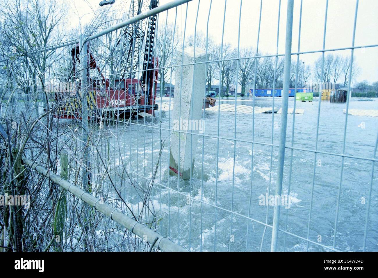 Rupture de tuyau d'eau R. Holkade, 09-03-1998 Whizgle News, Dutch Desk, pays-Bas, 1950-2000 Un chantier de construction partiellement immergé dans l'eau, avec de la machinerie lourde visible à l'arrière-plan. Une clôture entoure la zone et les arbres avoisinants sont partiellement submergés, ce qui illustre l'impact des inondations. Banque D'Images