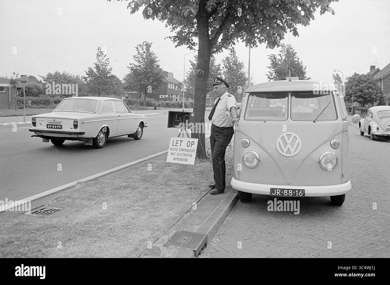 Contrôle de vitesse radar à Driehuis, police, 13-06-1973 Whizgle News, Dutch Desk, pays-Bas, 1950-2000 Un agent de la circulation se tient à côté d'une camionnette Volkswagen d'époque tout en surveillant la route. À proximité, une voiture classique passe et un panneau indique que la zone est soumise à la réglementation en matière de stationnement. Les rues bordées d'arbres et les bâtiments pittoresques créent un cadre serein. Banque D'Images