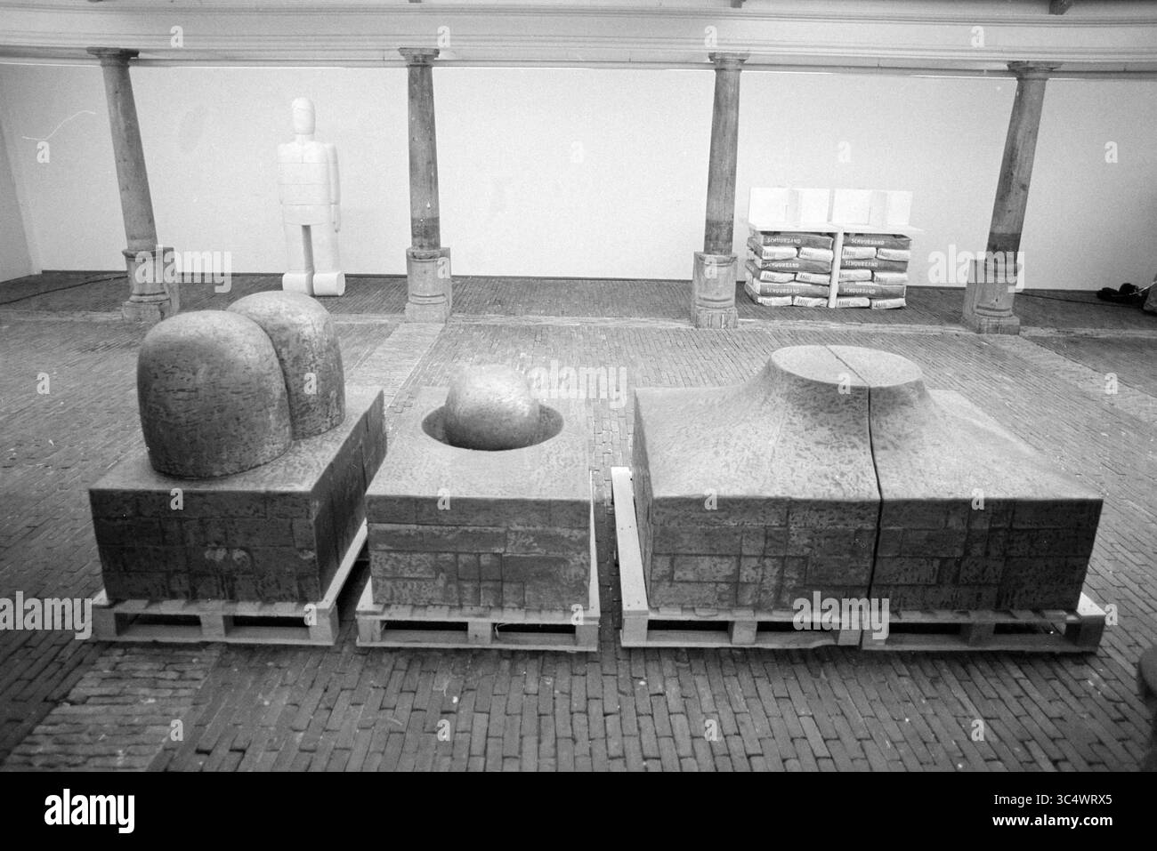 Œuvre d'art dans la halle des poissons, 12-11-1992 Whizgle News, Dutch Desk, pays-Bas, 1950-2000 un arrangement de grandes formes sculpturales en pierre, avec des formes géométriques comme des dômes et un cylindre arrondi, posées sur des palettes en bois dans une galerie spacieuse. Autour des sculptures se trouvent des colonnes et des piles de matériaux, ajoutant à l'ambiance artistique du décor. Banque D'Images