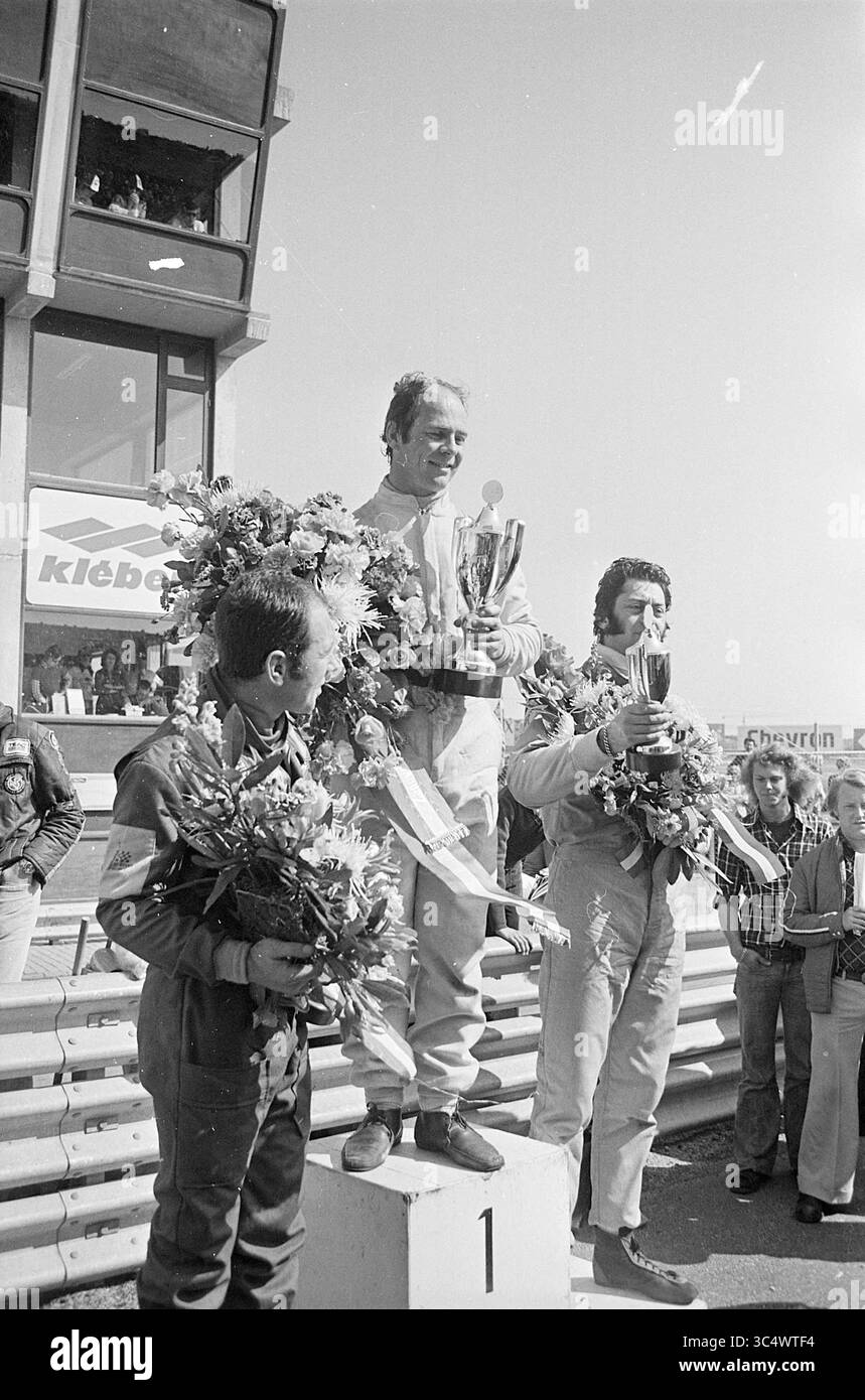 Autorace Zandvoort avec cérémonie de remise des prix, Zandvoort, 00-00-1975 Whizgle News, Dutch Desk, pays-Bas, 1950-2000 trois pilotes de voitures de course se tiennent sur un podium célébrant après une course. Le premier pilote détient un trophée et est orné de guirlandes florales, tandis que les deuxième et troisième pilotes affichent leurs récompenses. Une foule peut être vue en arrière-plan, exprimant l'excitation et l'admiration. Banque D'Images