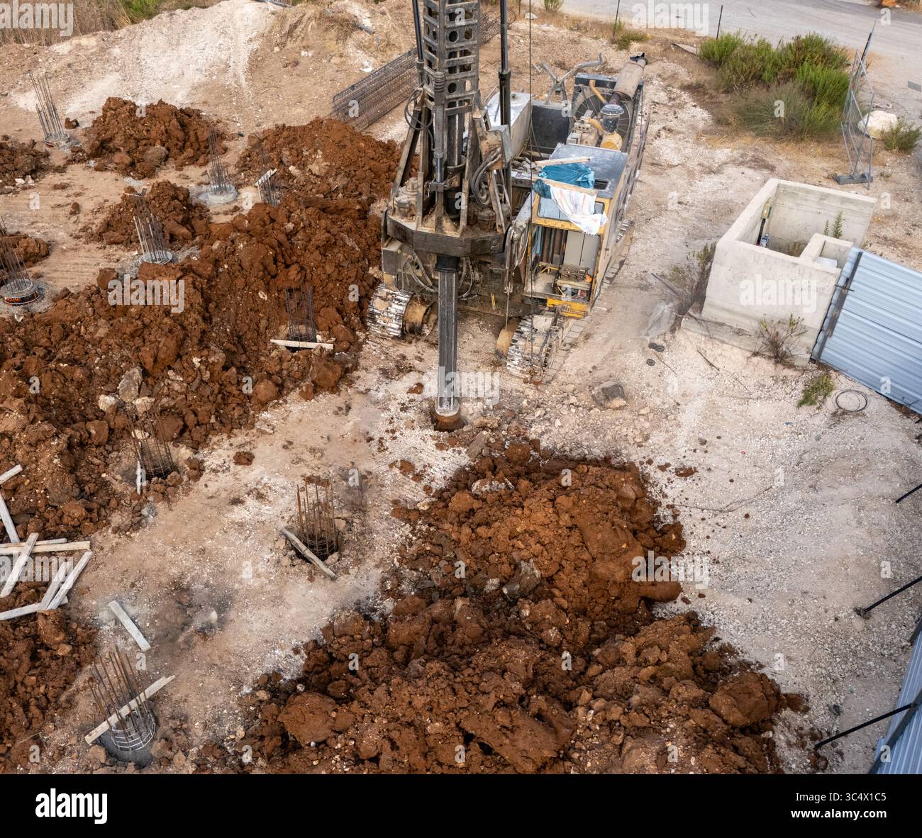 Vue aérienne d'un chantier de construction avec de la machinerie lourde creusant dans la terre, contrastant le sol brut contre les structures en béton, sa'Ar, North Distric Banque D'Images
