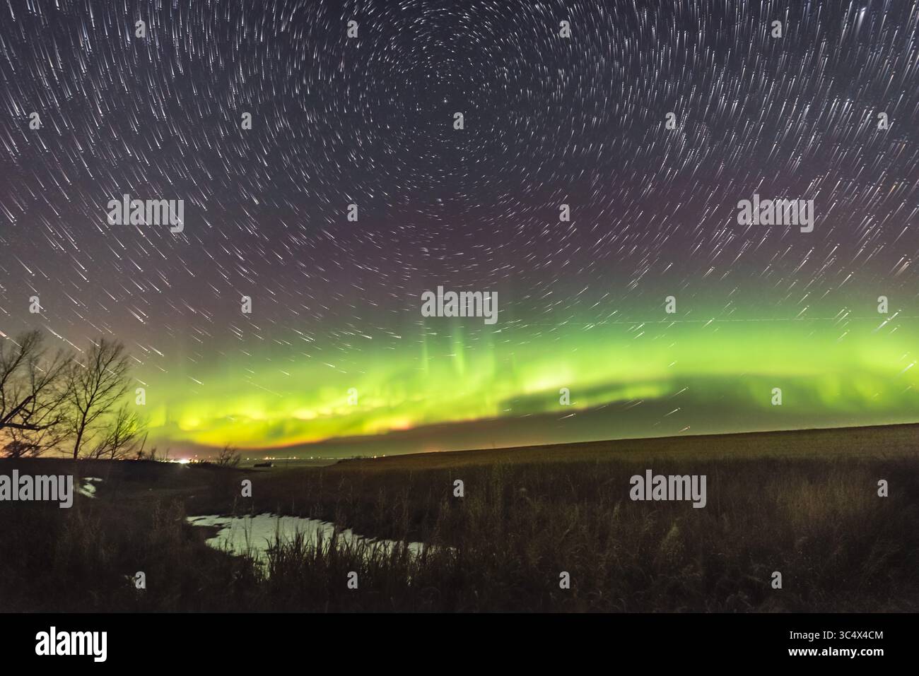 Le 13 octobre 2017 - Canada - Un composite de sentier d'étoiles circumpolaires avec aurores boréales, le 13 octobre 2017, tiré de chez nous dans le sud de l'Alberta... la Grande Dipper est au centre inférieur ; Polaris est au centre supérieur de l'axe de rotation. Le bord inférieur des rideaux est bordé d'une frange rose d'azote... il s'agit d'une pile de 200 cadres pris principalement lorsque l'aurore était un arc quiescent à travers le nord avant que la sous-orme ne frappe. Une exposition unique supplémentaire est superposée environ 1 minute après la mise en place du sillon de l'étoile principale pour ajouter les étoiles du point final après une lacune dans les sillons. Donc l'aurora Banque D'Images