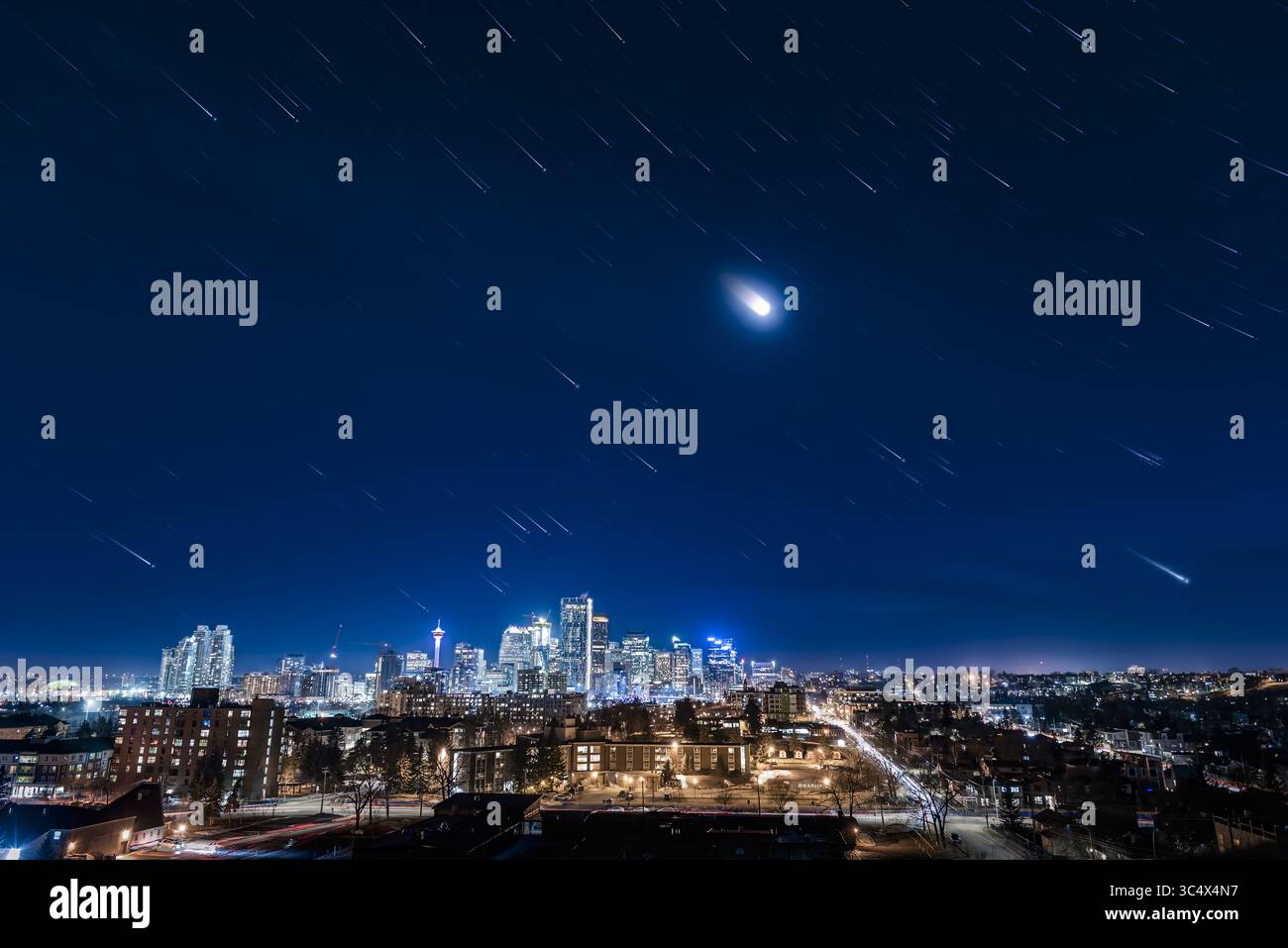 20 avril 2018 - Alberta, Canada - un sentier urbain des étoiles ! C'est possible ! ..il s'agit d'une pile de 275 expositions de 2 secondes pour créer les traces d'étoiles d'Orion, de la Lune, et les étoiles de l'hiver se plaçant au-dessus du centre-ville de Calgary le 19 avril 2018. Le ciel était brumeux, et bien sûr il y avait la pollution lumineuse de la ville et le clair de lune, mais la caméra a quand même capté un bon nombre d'étoiles. ..les 275 expositions alimentent le ciel et le sol. Une image finale, prise 1 minute après la dernière image de traînée d'étoiles, et fusionnée avec le mode éclaircir, ajoute les étoiles ponctuelles à la fin, pour mieux définir les constellations et m Banque D'Images
