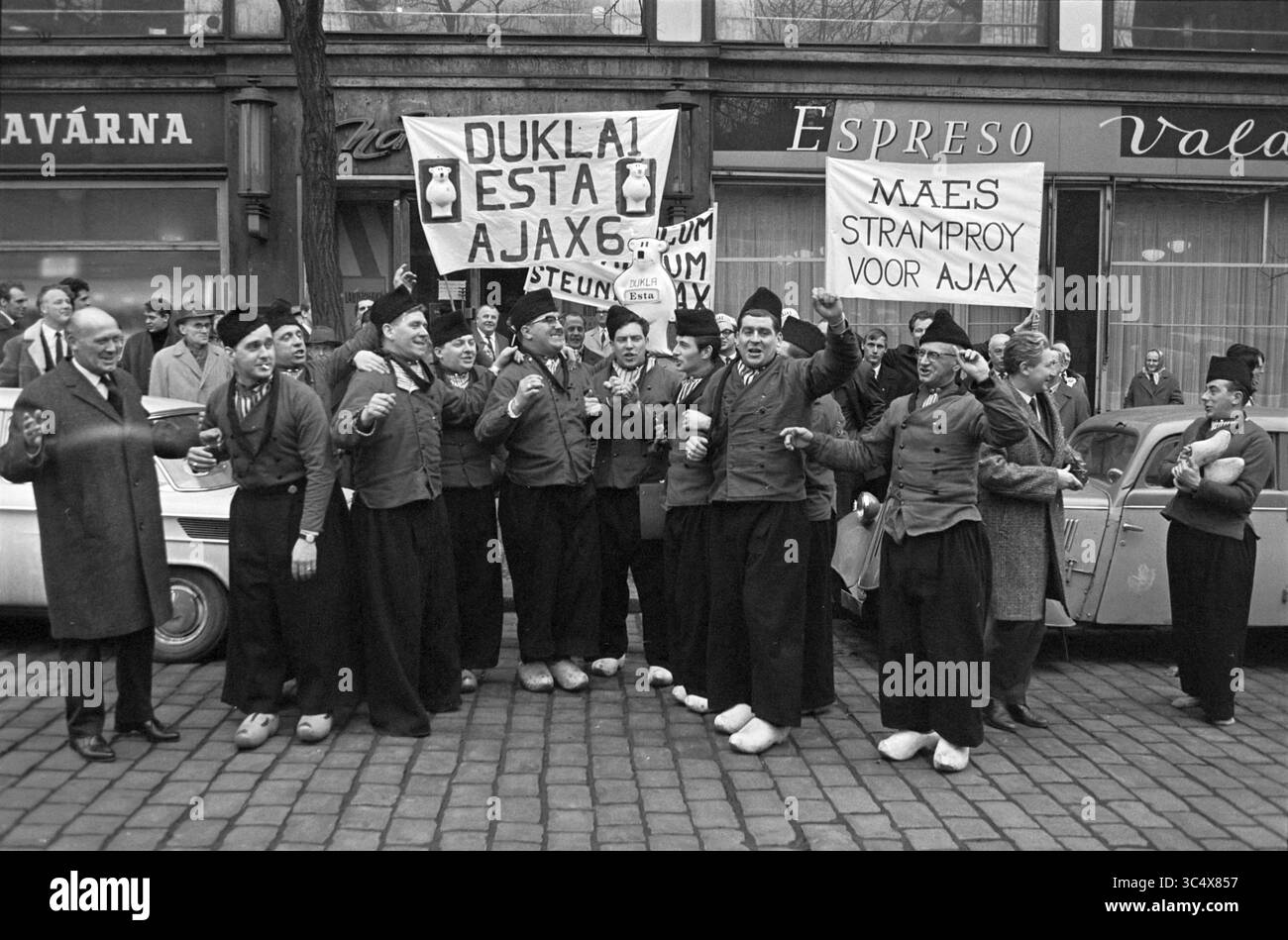 Coupe d'Europe 1 entre Dukla Prague et Ajax, score final 2-1. Forto rapport des fans à Prague et au stade. Willy Alberti est également présent dans le stade., Praag, Tsjechië, 08-03-1967 Whizgle News, Dutch Desk, pays-Bas, 1950-2000 Un groupe animé de supporters en tenue traditionnelle chante avec enthousiasme et se produit dans les rues, tenant des bannières qui font la promotion de leur équipe. L'atmosphère est remplie de camaraderie et de passion, reflétant l'esprit d'acclamer leur club de football préféré. En arrière-plan, une voiture classique et une foule ajoutent à la scène vibrante. Banque D'Images