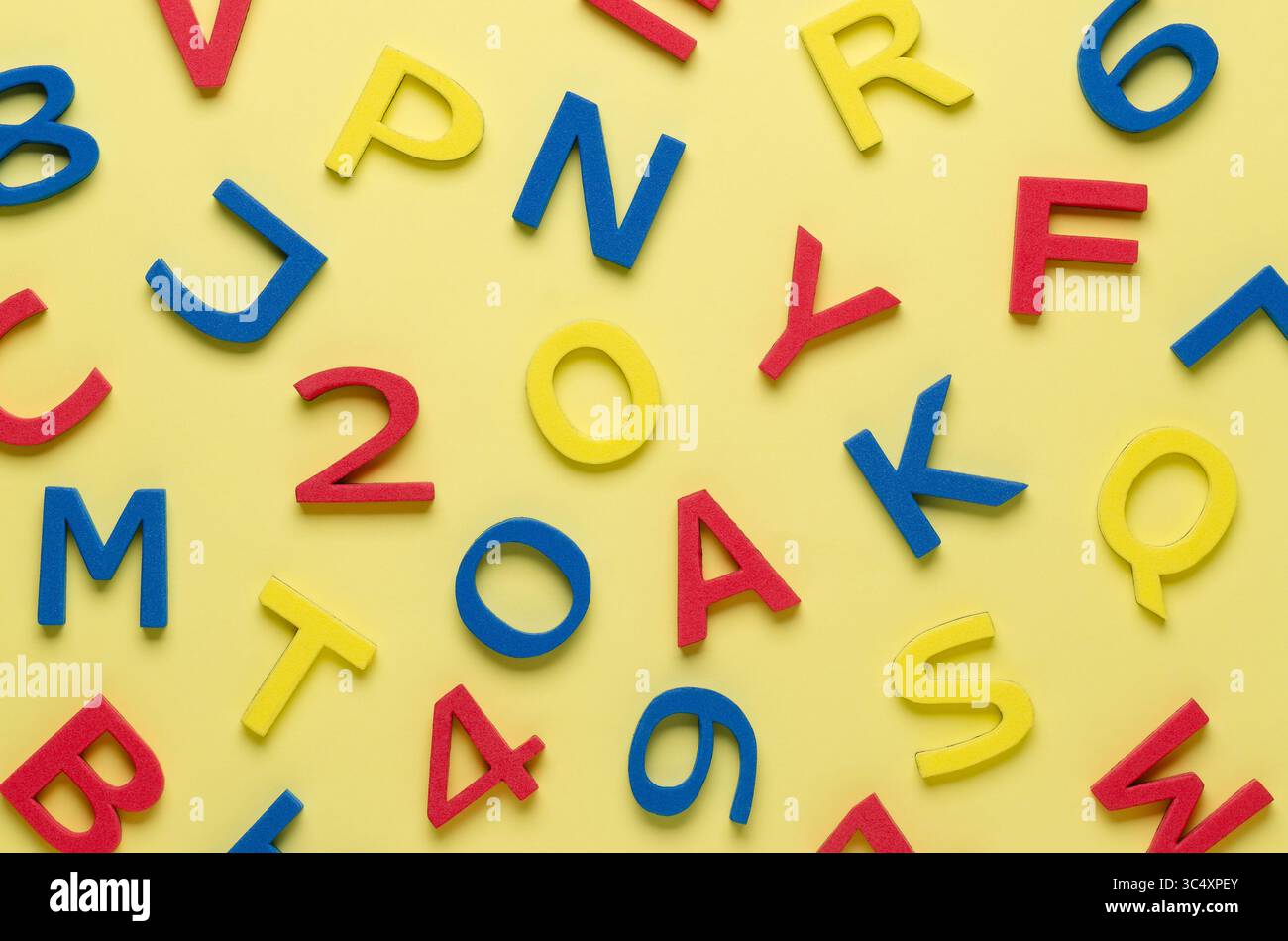 Lettres et chiffres colorés en mousse sur fond jaune. Banque D'Images Lettres et chiffres colorés en mousse sur fond jaune. Banque D'Images