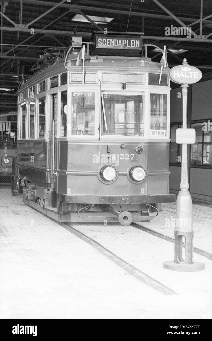 Old tram Museum NZH, Noord Zuid Hollandse Vervoersmaatschappij N.V., NZ, Tram, 05-11-1986 Whizgle News, Dutch Desk, pays-Bas, 1950-2000 Un tramway d'époque avec un panneau de destination indiquant 'Schoenaplein' se trouve à une gare, tandis qu'un poteau voisin marqué 'Halte' indique un arrêt. Le cadre offre une atmosphère industrielle, avec des pistes menant à un terminal spacieux. Banque D'Images