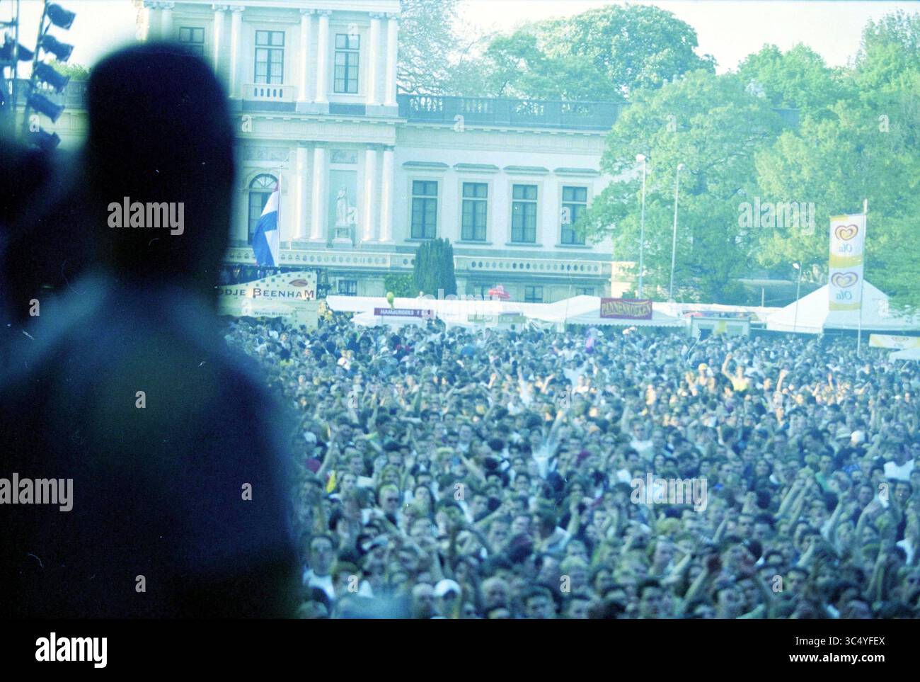 Poupée libération, Haarlem, pays-Bas, 04-05-2000 Whizgle News, Dutch Desk, pays-Bas, 1950-2000 Une foule nombreuse se rassemble devant un grand bâtiment, les mains levées dans l'excitation, alors qu'une performance se déroule sur scène. Les tentes et les bannières indiquent une atmosphère de festival animée, entourée d'arbres et d'une toile de fond historique. Banque D'Images