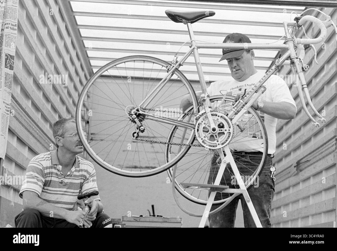 Mosquito Round, SP'woude, Spaarnwoude, 14-08-1994 Whizgle News, Dutch Desk, pays-Bas, 1950-2000 deux hommes travaillent ensemble pour assembler un vélo. Un homme se concentre sur l'ajustement du vélo tandis que l'autre regarde attentivement de côté, offrant probablement de l'aide ou des conseils. Les outils et l'équipement peuvent être vus à proximité, indiquant un environnement pratique d'entretien ou d'assemblage de bicyclettes. Banque D'Images