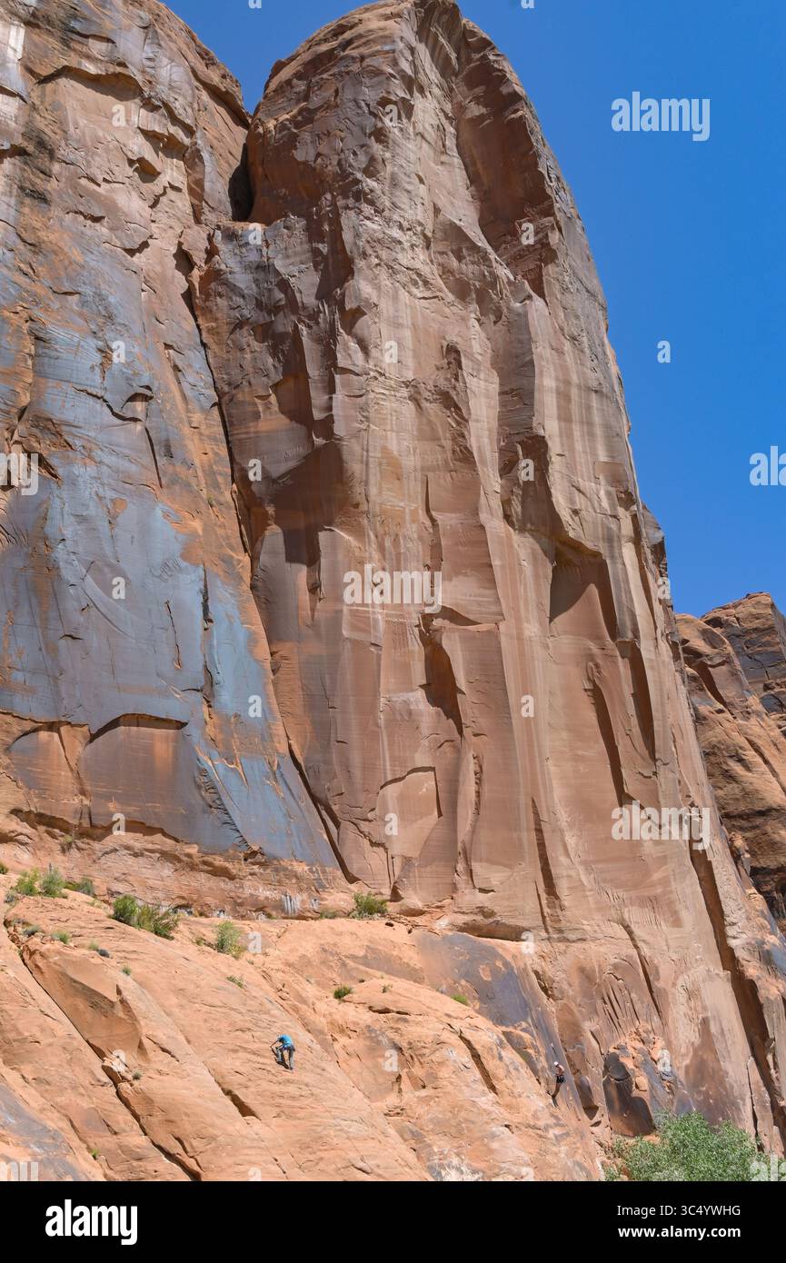 Moab, Utah, États-Unis - 25 mai 2025 : grimpeur debout sur une paroi rocheuse ancrée par des cordes d'escalade montrant l'échelle de la montagne Banque D'Images