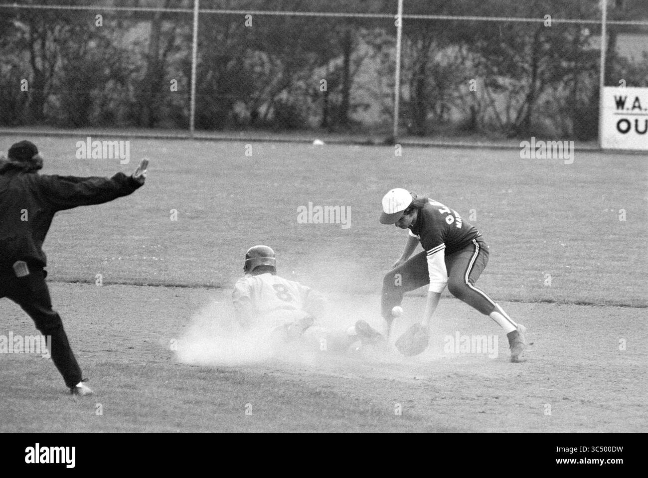 Nicols - Ado, Baseball, 24-05-1975 Whizgle News, Dutch Desk, pays-Bas, 1950-2000 Un joueur de baseball glisse dans la base, dégageant un nuage de poussière, tandis que le joueur adverse tente de l'étiqueter. Un arbitre signale en arrière-plan, capturant un moment d'action intense sur le terrain. Banque D'Images
