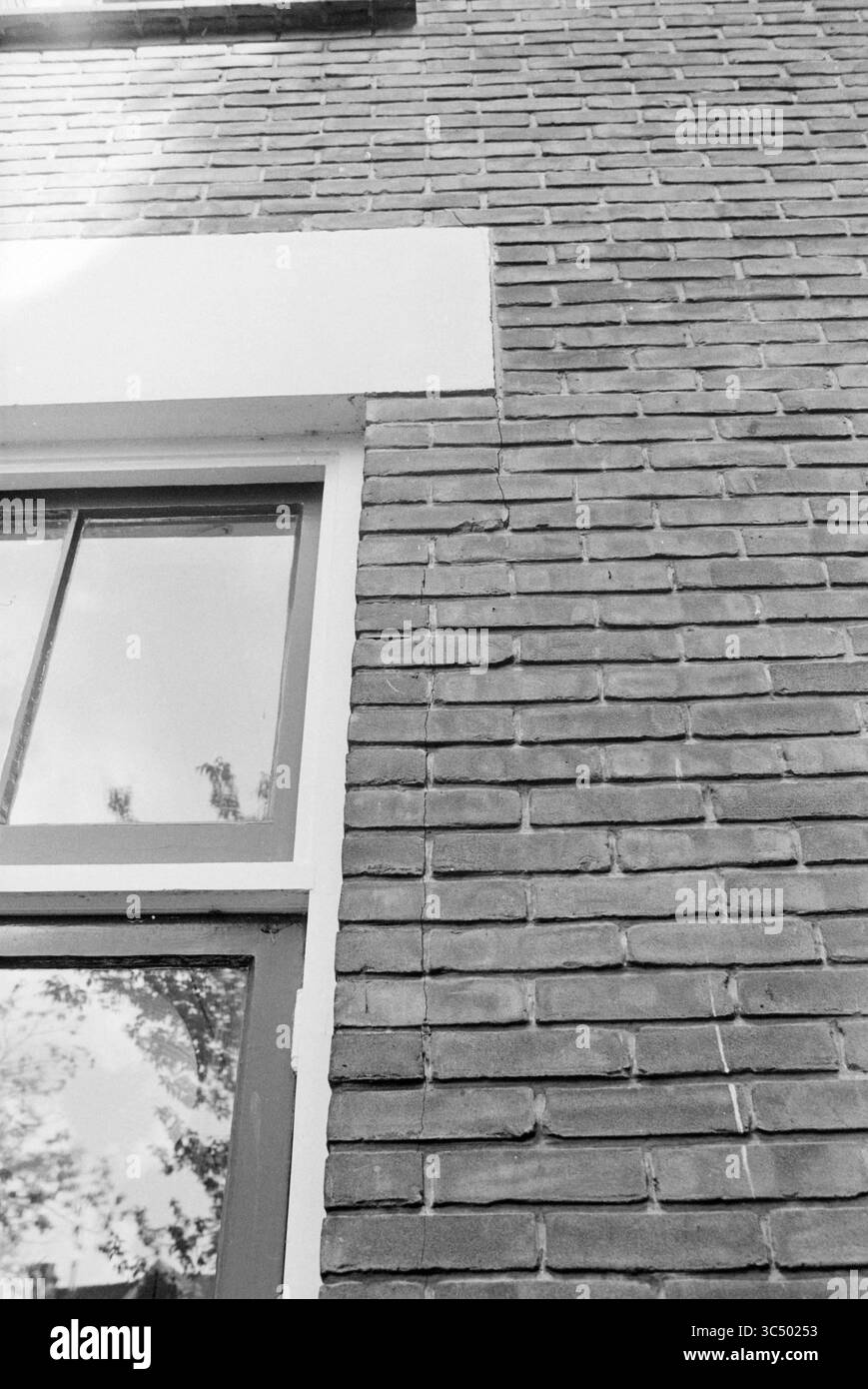 Fissures dans le bâtiment de Gottmer Publishers, bâtiments, 12-09-1986 Whizgle News, Dutch Desk, pays-Bas, 1950-2000 Un mur de briques texturées présente une bordure blanche au-dessus d'une fenêtre, avec des reflets subtils visibles sur le verre, capturant un aperçu de l'environnement. Banque D'Images