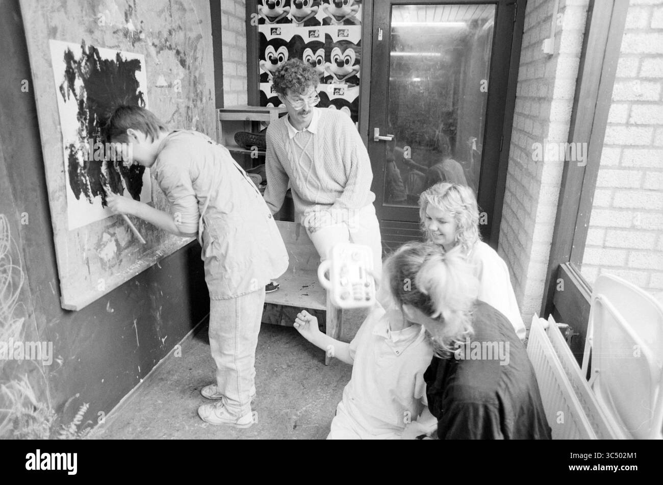 Garderie pour handicapés, Hoofddorp, garderies, Hoofddorp, pays-Bas, 28-09-1988 Whizgle News, Dutch Desk, pays-Bas, 1950-2000 Un groupe de quatre personnes se livre à une activité artistique, une personne peignant sur une grande toile tandis que les autres observent et interagissent. Le cadre semble être un espace créatif, rempli d’une atmosphère de collaboration et d’expression artistique. Banque D'Images