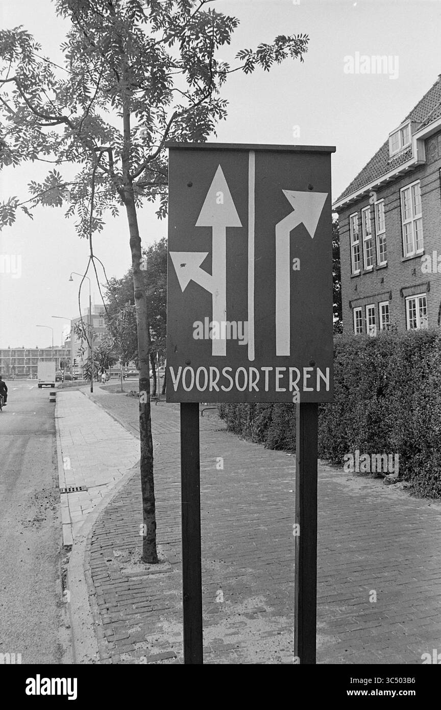 Plaques de pré-tri, plaques, 14-08-1969 Whizgle News, Dutch Desk, pays-Bas, 1950-2000 Un panneau routier comporte des flèches directionnelles indiquant les voies pour les virages à gauche, en ligne droite et à droite, avec le mot « VOORSORTEREN » bien en évidence ci-dessous. Autour du panneau se trouvent des arbres et une rue bordée, menant à une zone plus urbaine en arrière-plan. Banque D'Images