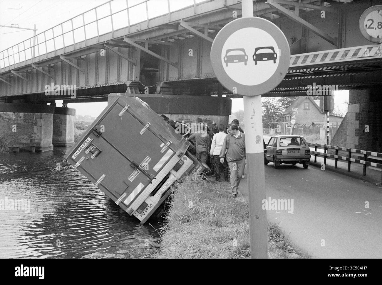 Accident au viaduc ferroviaire de Leidsevaart Vogelenzang, 26-09-1988 Whizgle News, Dutch Desk, pays-Bas, 1950-2000 Un groupe de personnes se tient près d'un canal près d'un camion partiellement tombé à l'eau, avec un pont au-dessus et un panneau de signalisation indiquant une restriction de hauteur à proximité. Banque D'Images