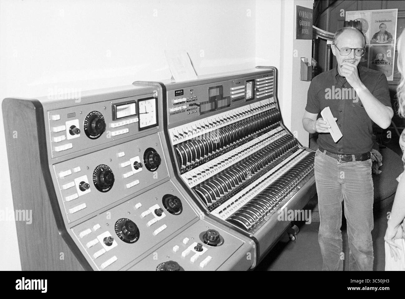 Nouvel orgue Stadsschouwburg, Théâtre, éclairage, 30-08-1979 Whizgle News, Dutch Desk, pays-Bas, 1950-2000 Un homme se tient à côté d'un panneau de commande vintage rempli de nombreux cadrans, interrupteurs et lumières, profondément dans la pensée tout en tenant un morceau de papier. Les environs présentent un soupçon de design industriel, indiquant un environnement high-tech du passé. Banque D'Images