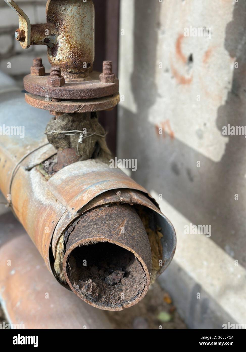 Tuyau industriel rouillé avec valve corrodée et fond de peinture pelable. Abandon des communications de bâtiment et mauvais entretien Banque D'Images