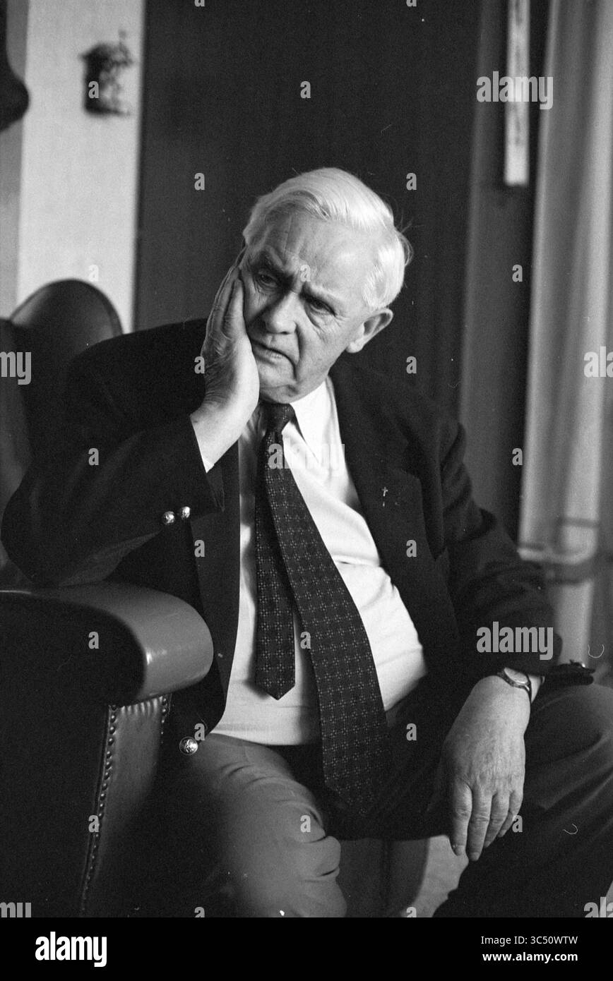 Pastor Voets, Alphen aan de Rijn, Église catholique romaine, Alphen aan den Rijn, 10-01-1990 Whizgle News, Dutch Desk, pays-Bas, 1950-2000 un homme plus âgé est assis avec soin dans un fauteuil, posant son menton sur sa main. Il est habillé d'un costume et d'une cravate, exsudant un sens de contemplation et de sagesse alors qu'il regarde au loin, peut-être perdu dans la réflexion. Le cadre transmet une atmosphère calme et introspective. Banque D'Images