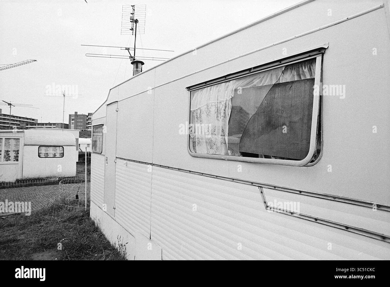 Dommages à la caravane. Whizgle News, Dutch Desk, pays-Bas, 1950-2000 Une caravane altérée se trouve dans un espace extérieur compact, avec une fenêtre avec des rideaux de dentelle partiellement dessinés. Les structures et les grues à proximité font allusion à une toile de fond urbaine en évolution, contrastant avec la simplicité du mobil-home. Banque D'Images Dommages à la caravane. Whizgle News, Dutch Desk, pays-Bas, 1950-2000 Une caravane altérée se trouve dans un espace extérieur compact, avec une fenêtre avec des rideaux de dentelle partiellement dessinés. Les structures et les grues à proximité font allusion à une toile de fond urbaine en évolution, contrastant avec la simplicité du mobil-home. Banque D'Images