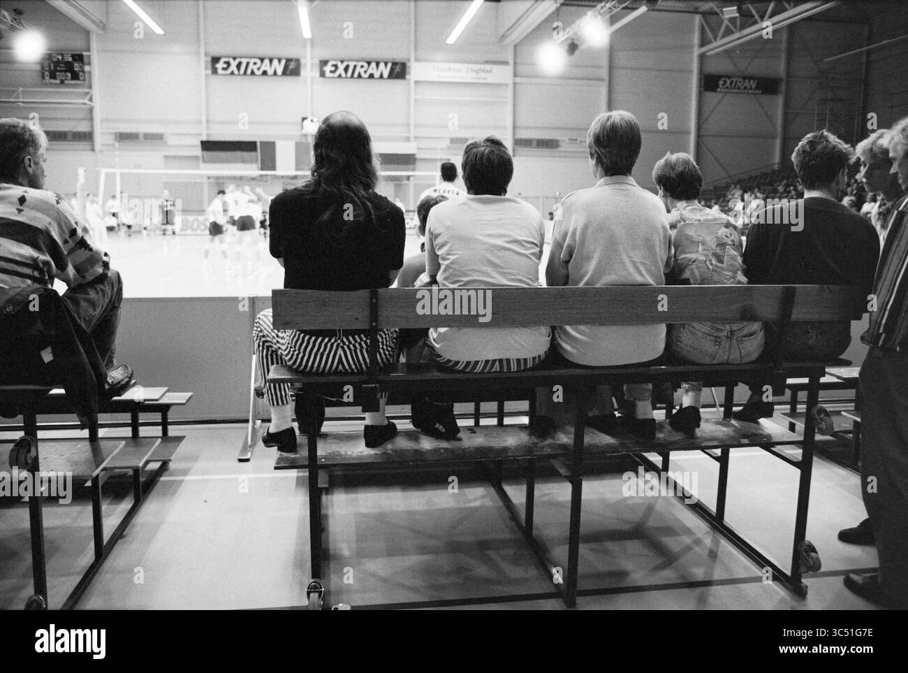 1 an Extran hall, Haarlem, pays-Bas, 31-08-1994 Whizgle News, Dutch Desk, pays-Bas, 1950-2000 Un groupe de spectateurs s'assoit sur un banc, observant un match de volley-ball au loin, leur accent étant mis sur les joueurs engagés dans le match. L'atmosphère suggère l'excitation et l'anticipation au fur et à mesure que le jeu se déroule. Banque D'Images