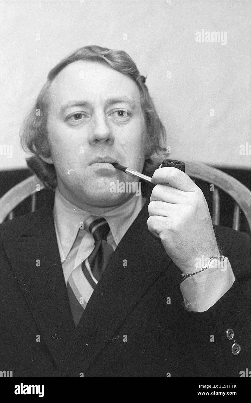 M. de Rooy Directeur adjoint N.B. T., Portraits, 14-01-1974 Whizgle News, Dutch Desk, pays-Bas, 1950-2000 Un homme bien habillé assis dans une chaise, tenant soigneusement une pipe. Il a une expression contemplative et porte une cravate qui ajoute une touche de style à son ensemble. Ses cheveux sont coiffés en vagues douces, contribuant à une apparence classique. Banque D'Images
