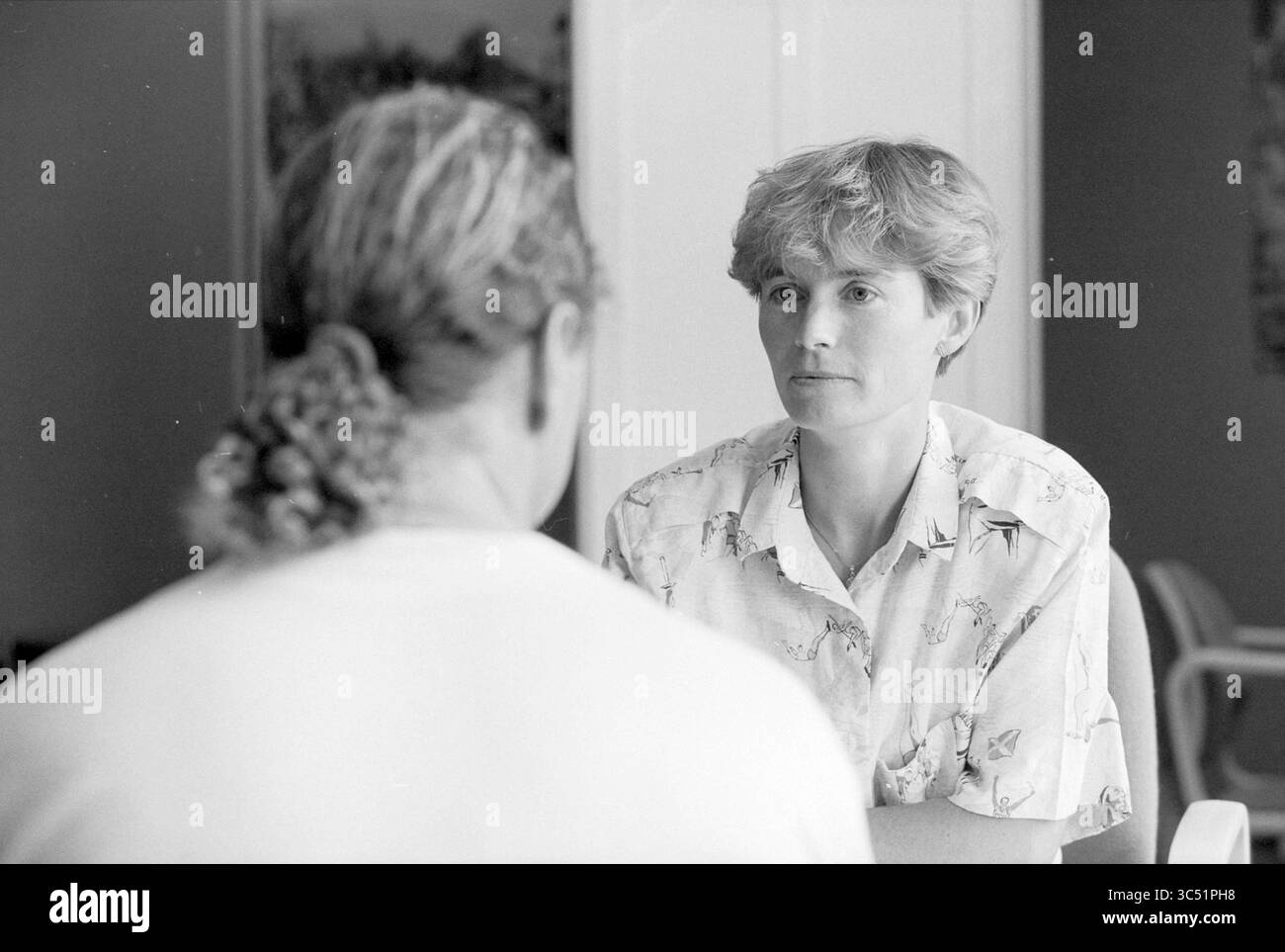 Youth and moral police A.V. Borrows, 03-08-1992 Whizgle News, Dutch Desk, pays-Bas, 1950-2000 deux personnes sont engagées dans une conversation intense, une personne visiblement concentrée sur l'autre. Le cadre semble détendu, faisant allusion à une discussion personnelle ou intime. L’individu aux cheveux courts écoute attentivement, transmet curiosité ou inquiétude, tandis que l’autre est partiellement détourné, suggérant un moment de réflexion ou de partage. Banque D'Images