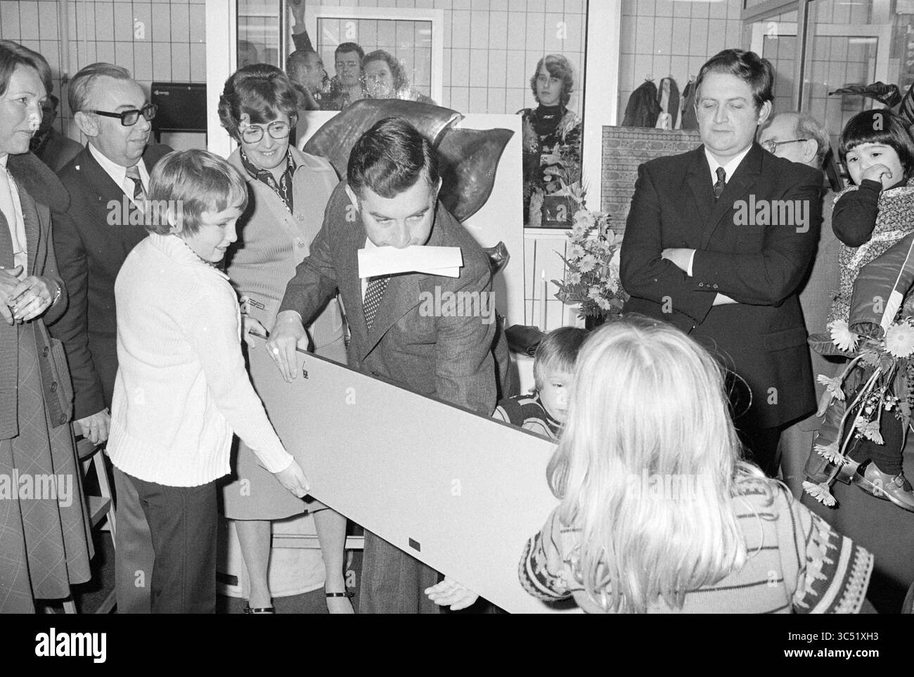 Ouverture de l'abattoir Fa. par. Lions, H'lem, ouverture, ouvertures, inauguration, 15-11-1976 Whizgle News, Dutch Desk, pays-Bas, 1950-2000 Un groupe d'adultes et d'enfants se réunit autour d'un homme en costume qui se prépare à couper un grand ruban. L'atmosphère est festive, certains participants observant avec impatience, tandis que d'autres tiennent des accessoires, faisant allusion à un événement spécial ou à une célébration. Banque D'Images