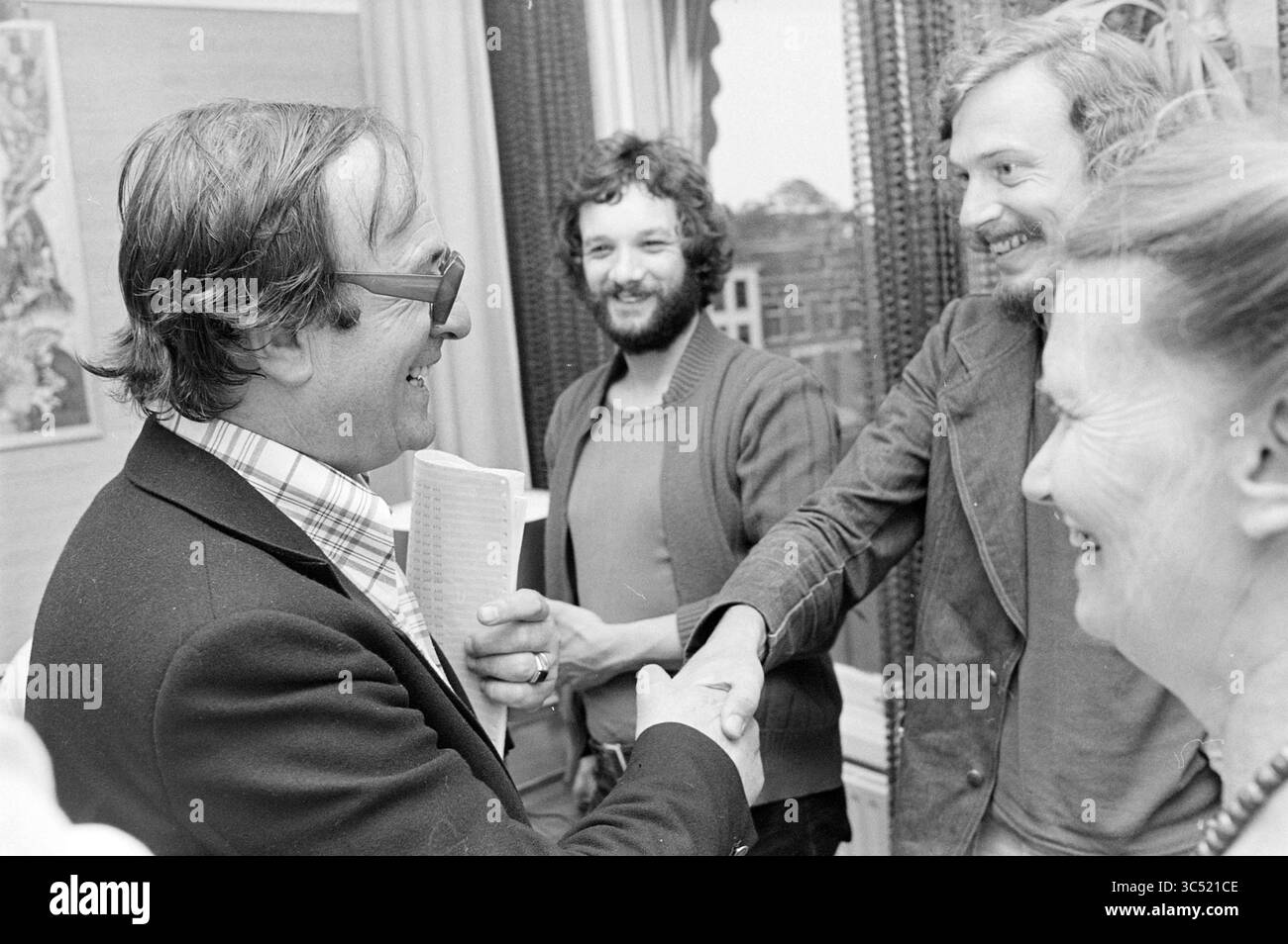 Dépouillement des votes au C.V.A. avec les partis politiques, élections, 25-05-1977 Whizgle News, Dutch Desk, pays-Bas, 1950-2000 Un groupe de quatre personnes s'engage dans la conversation et le rire, un homme serrant la main d'un autre. L’ambiance semble conviviale et détendue, suggérant un moment de camaraderie entre eux. Le cadre comprend des fenêtres avec des rideaux décoratifs, faisant allusion à un environnement intérieur confortable. Banque D'Images
