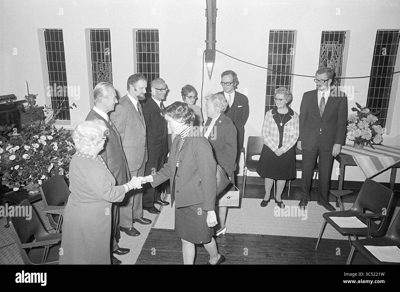 Réception, 00-00-1972 Whizgle News, Dutch Desk, pays-Bas, 1950-2000 Un groupe de personnes en tenue formelle est réuni dans un cadre intérieur, engageant la conversation et des poignées de main. Certains participants semblent accueillir les nouveaux arrivants, tandis que d'autres se tiennent par paires ou en petits groupes, entourés de plantes décoratives et d'arrangements floraux. L'atmosphère transmet un sentiment de communauté et de connexion. Banque D'Images