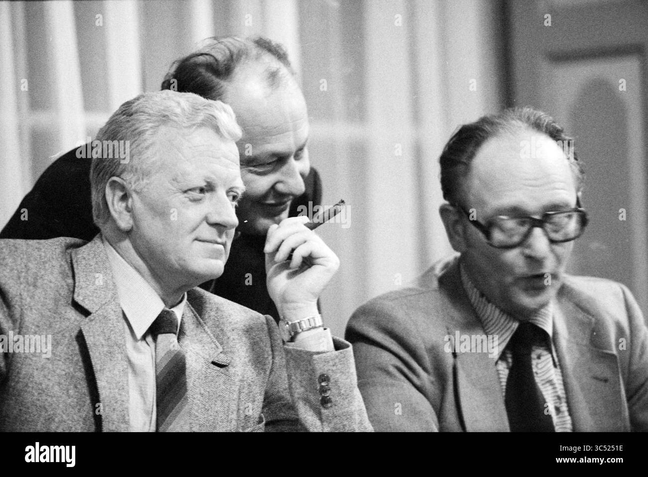 Débats budgétaires, conseil de Haarlem, Conseil municipal de Haarlem, Haarlem, pays-Bas, 07-11-1979 Whizgle News, Dutch Desk, pays-Bas, 1950-2000 trois hommes s'engagent dans la conversation, l'un tenant un cigare et paraissant contemplatif, tandis qu'un autre se penche, apparemment intrigué. Le troisième homme agit de manière animée, contribuant à une discussion animée. Banque D'Images