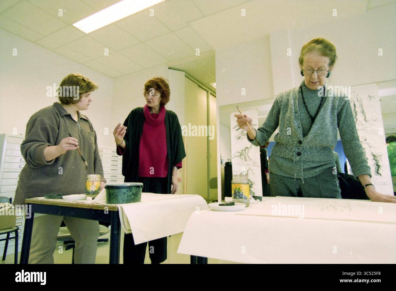 Cours de pinceau oriental, Hoofddorp, pays-Bas, 05-02-1999 Whizgle News, Dutch Desk, pays-Bas, 1950-2000 trois femmes sont engagées dans une session d'art créatif, entourées de fournitures. Une femme fait des gestes pendant qu'elle parle, tandis qu'une autre se concentre sur sa peinture, et la troisième observe. L’atmosphère reflète la collaboration et la créativité dans un espace artistique. Banque D'Images